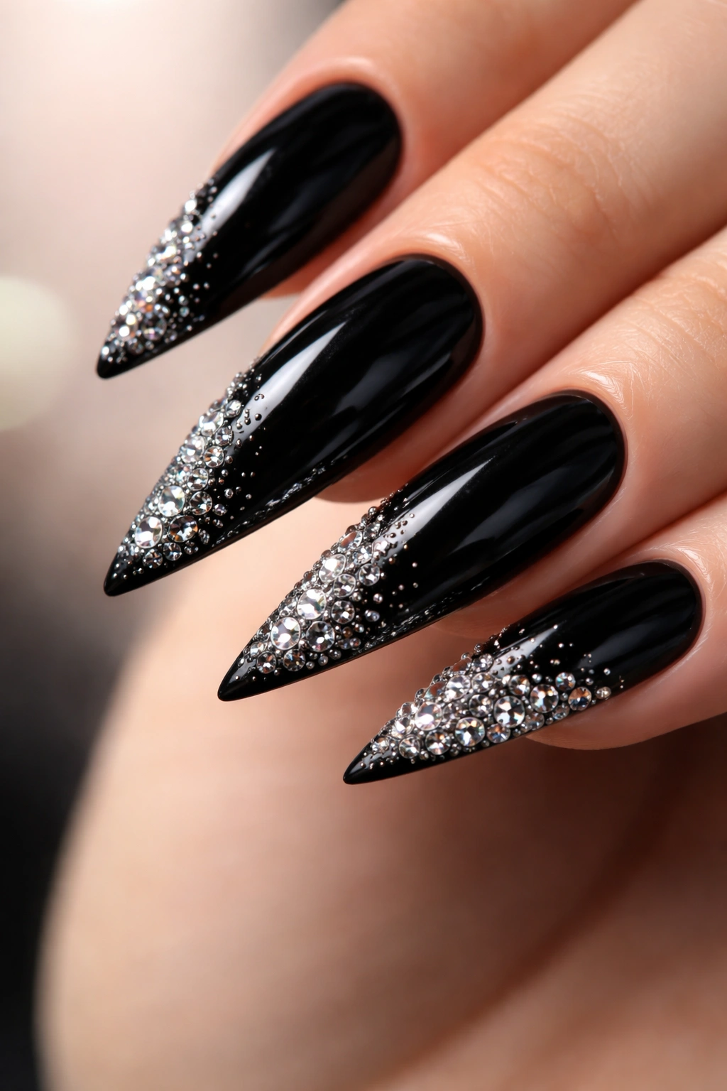 Black stiletto nails with a rhinestone gradient from dense to sparse