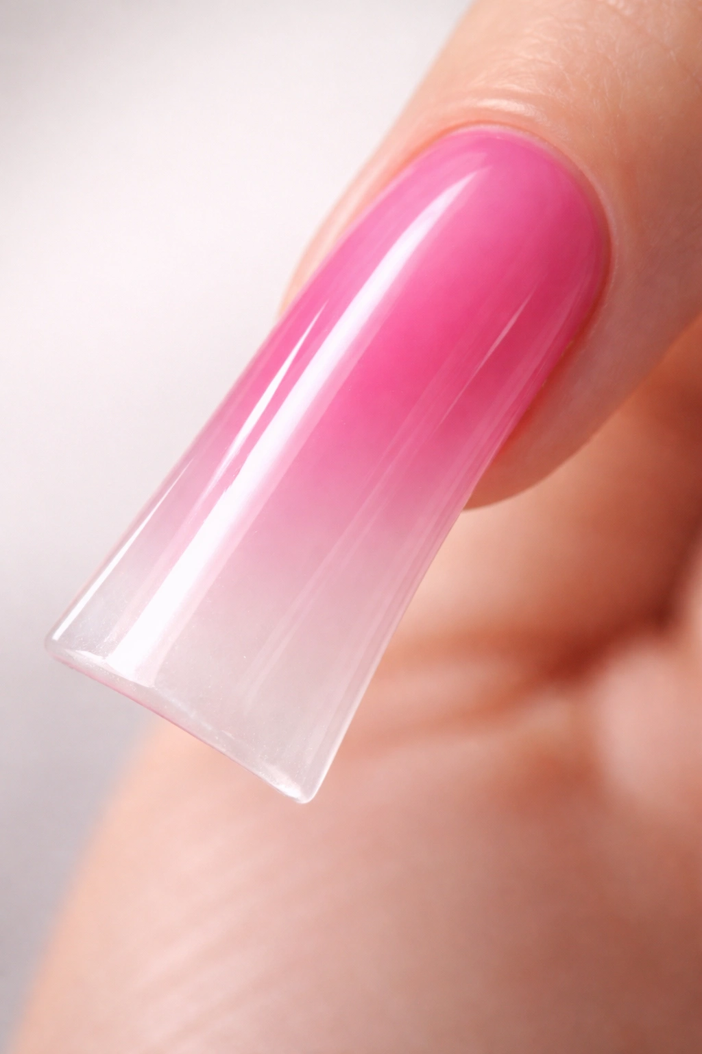 Close-up of a long duck nail with ombré hot pink to white jelly finish