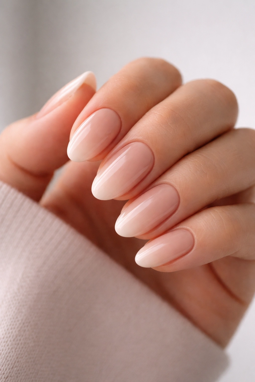 Close-up of neutral ombré almond nails with pink to beige gradient on short nails