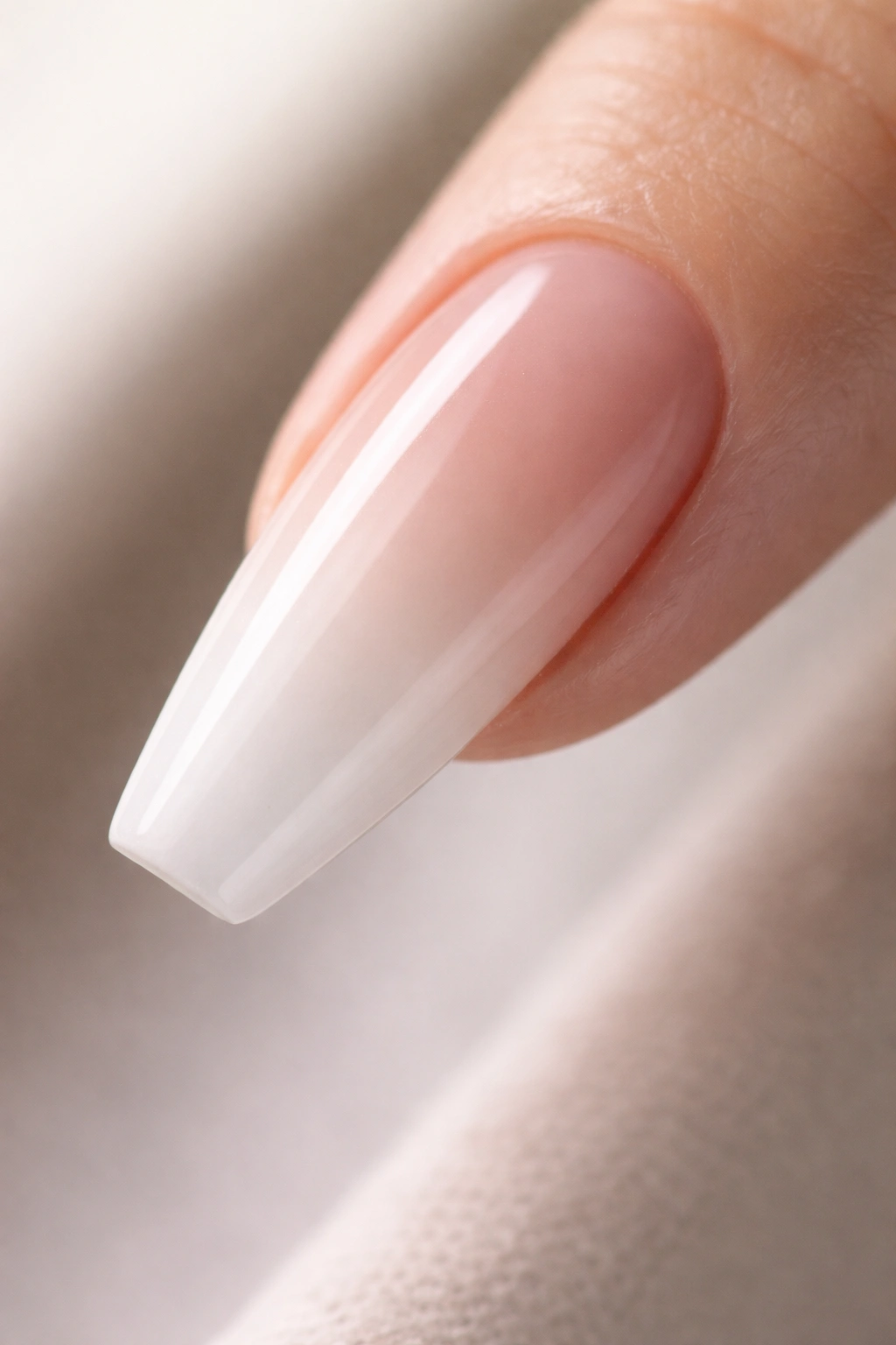 Close-up of a ballerina nail with a nude-to-ombre gradient and elongated tip