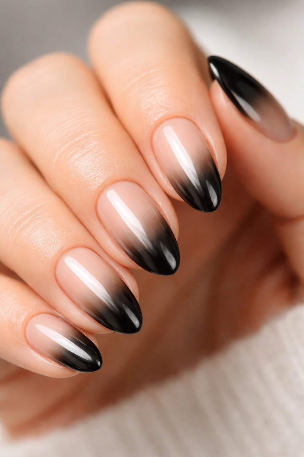 Close-up of short almond nails with nude-to-black chrome ombre fade