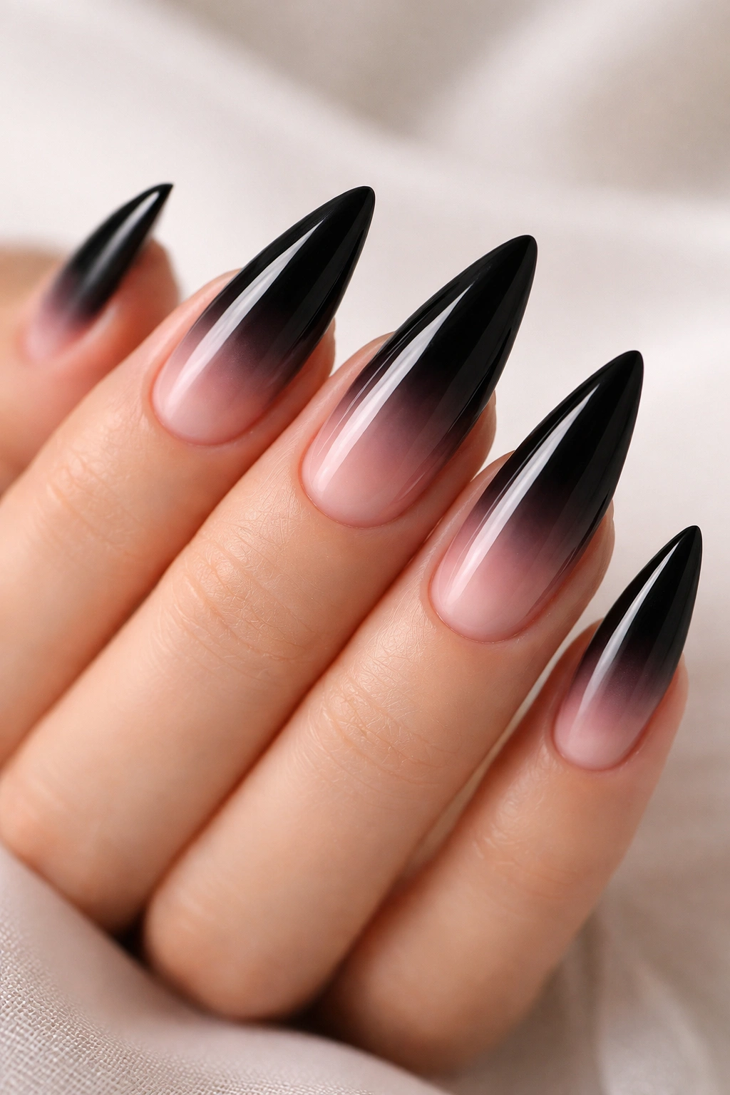Ombré nails transitioning from black to sheer pink on stiletto tips