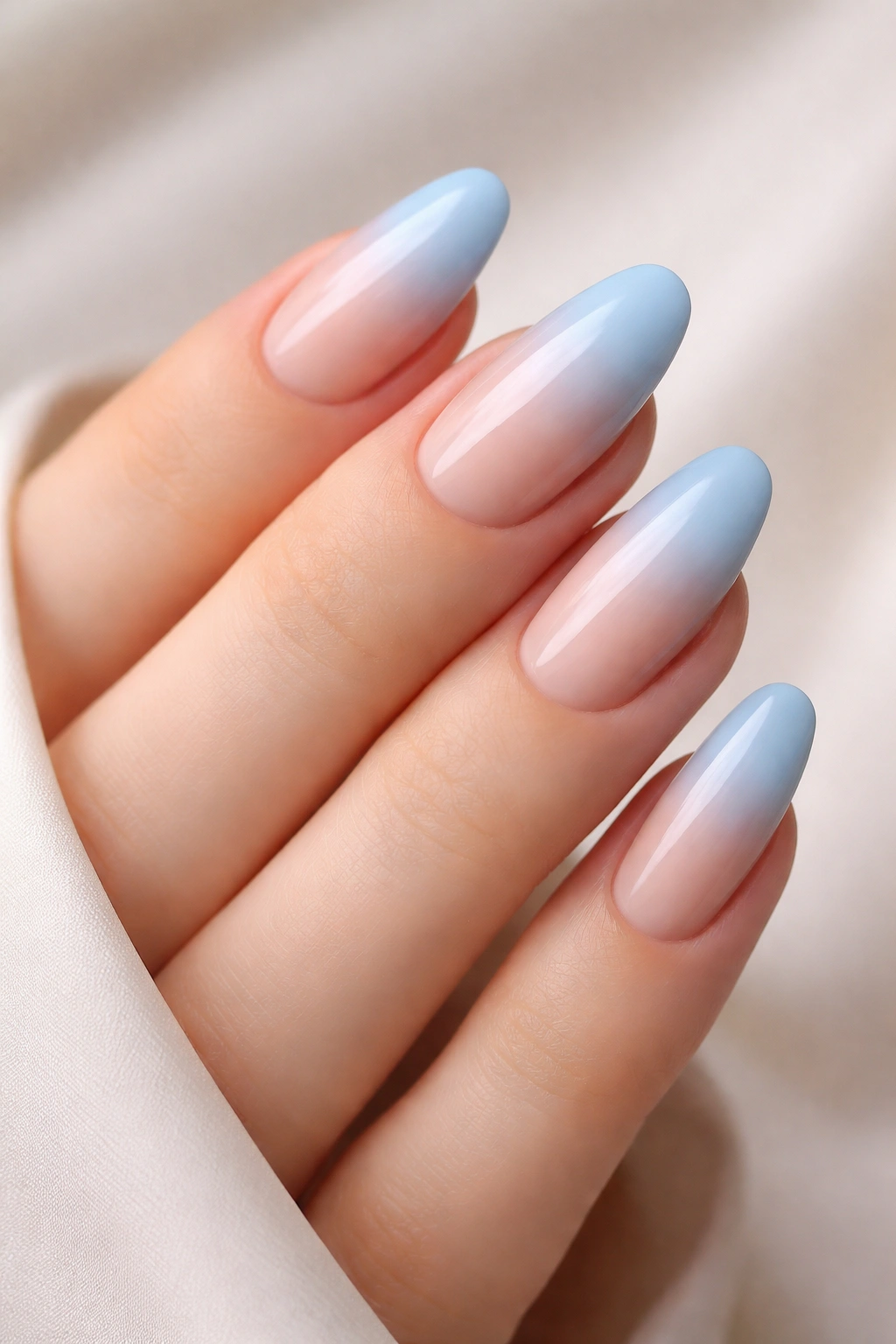 Close-up of soft sky blue ombre nails fading to nude base