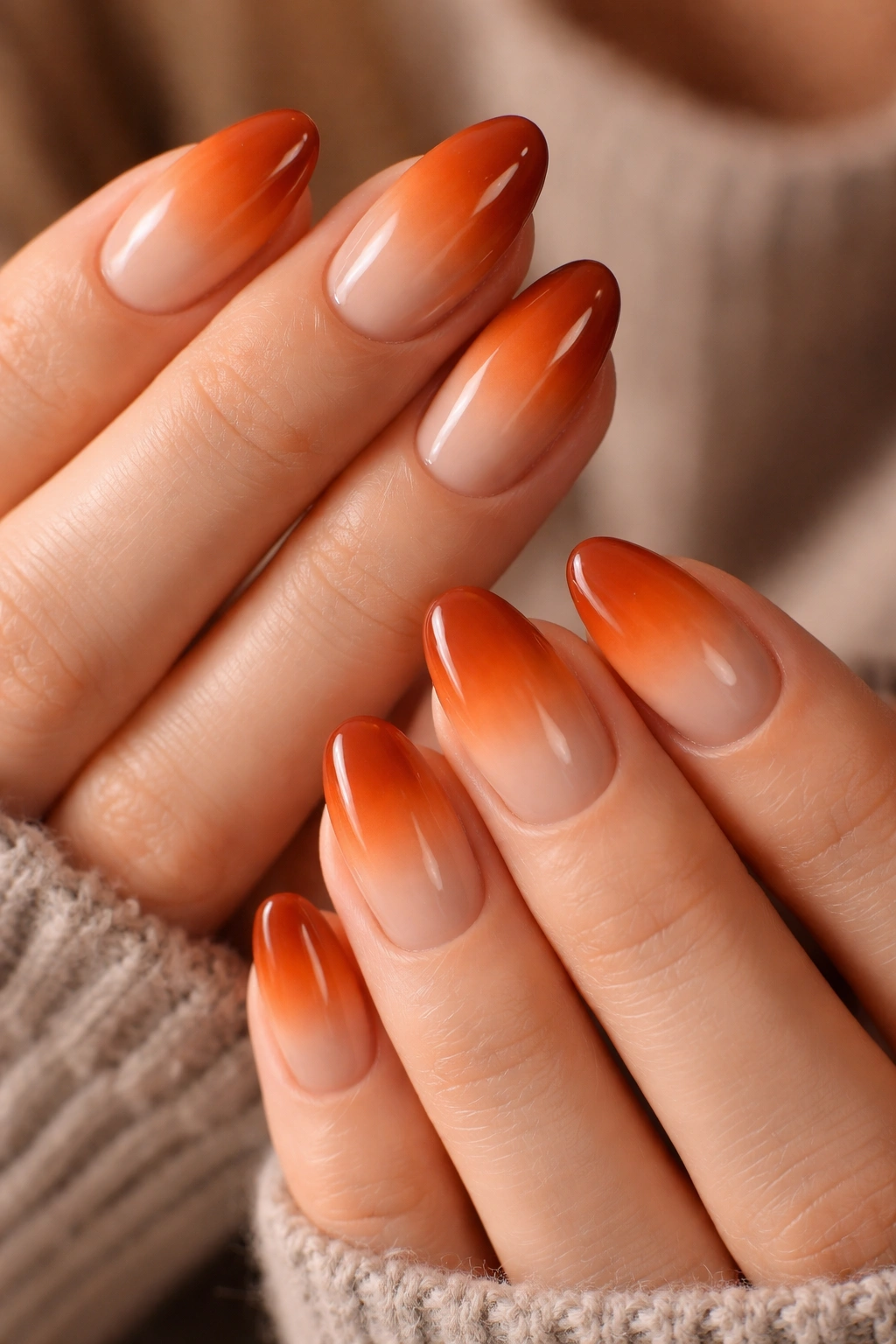 Close-up of short almond nails with burnt orange to nude ombre