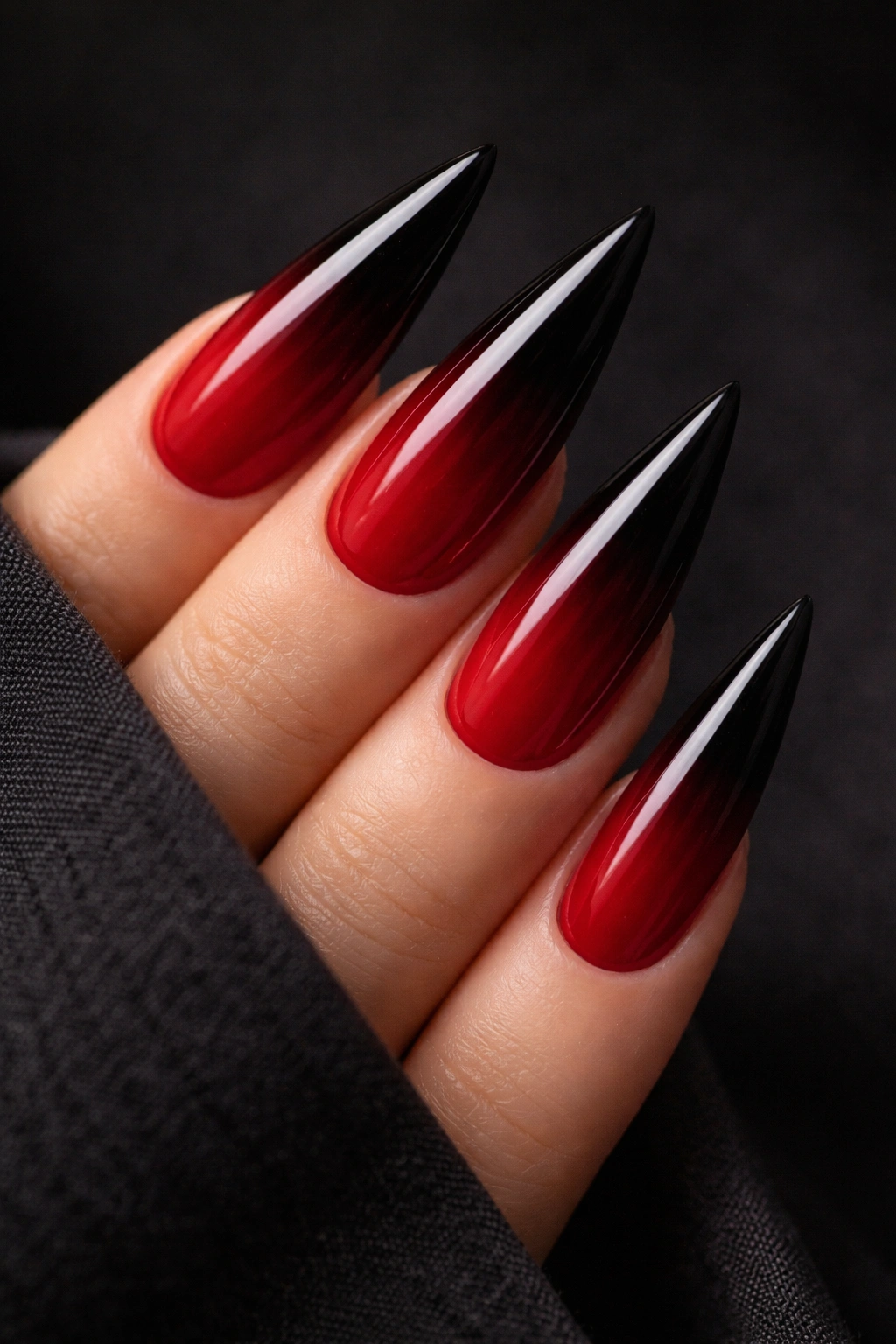 Close-up of stiletto nails with cherry red to black ombré gradient