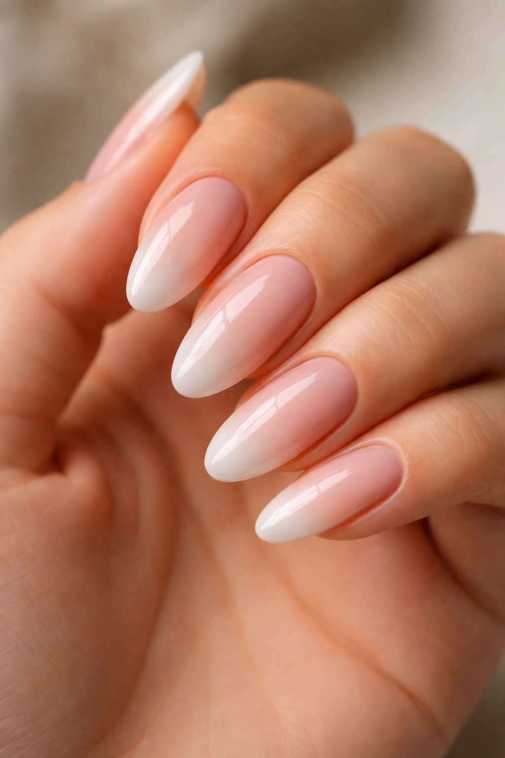 Close-up of long oval nails with glossy ombre finish on a natural hand