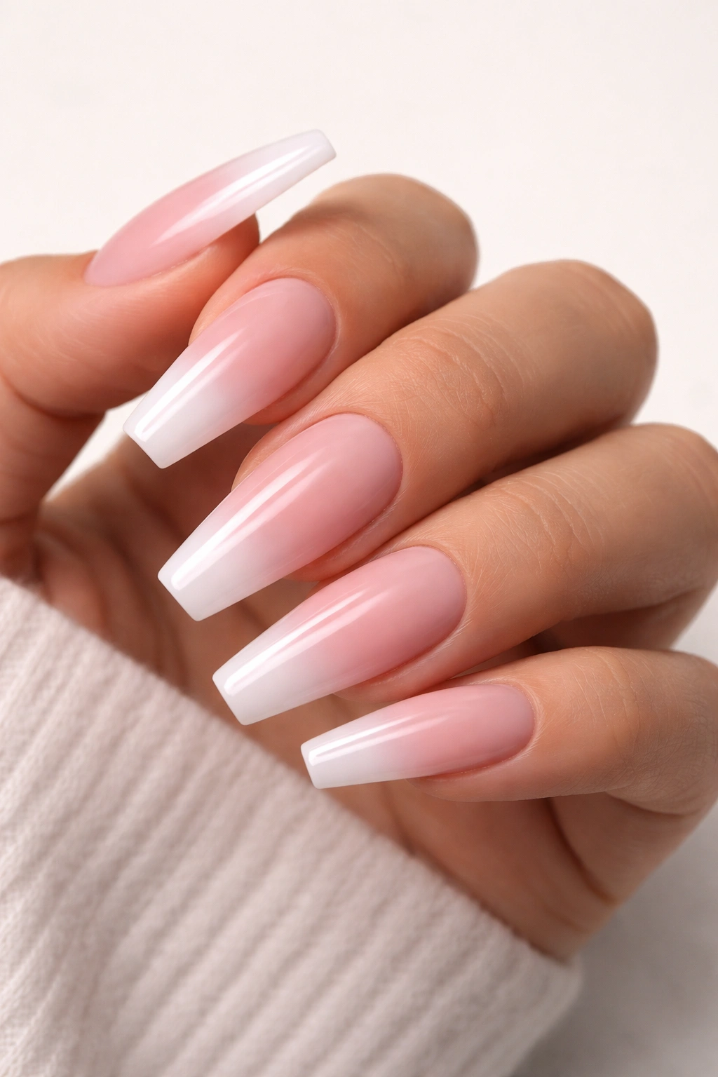 Nails with nude-to-pink ombre gradient on coffin shape.