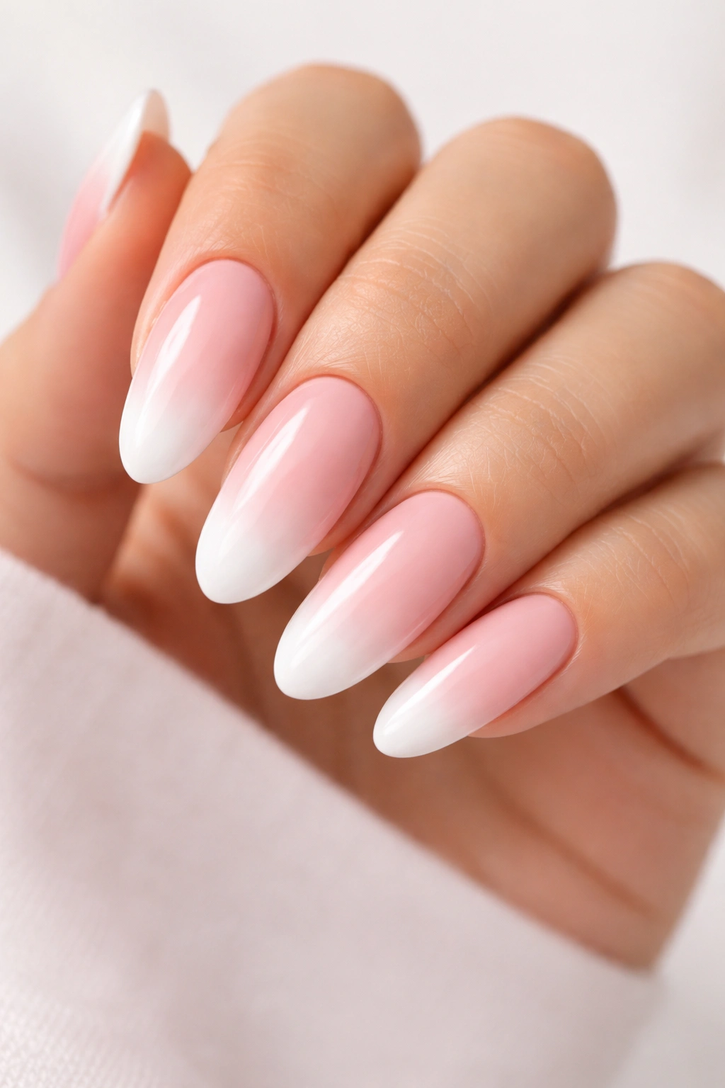 Ombré blush to white gradient nails on long round nails in natural light.