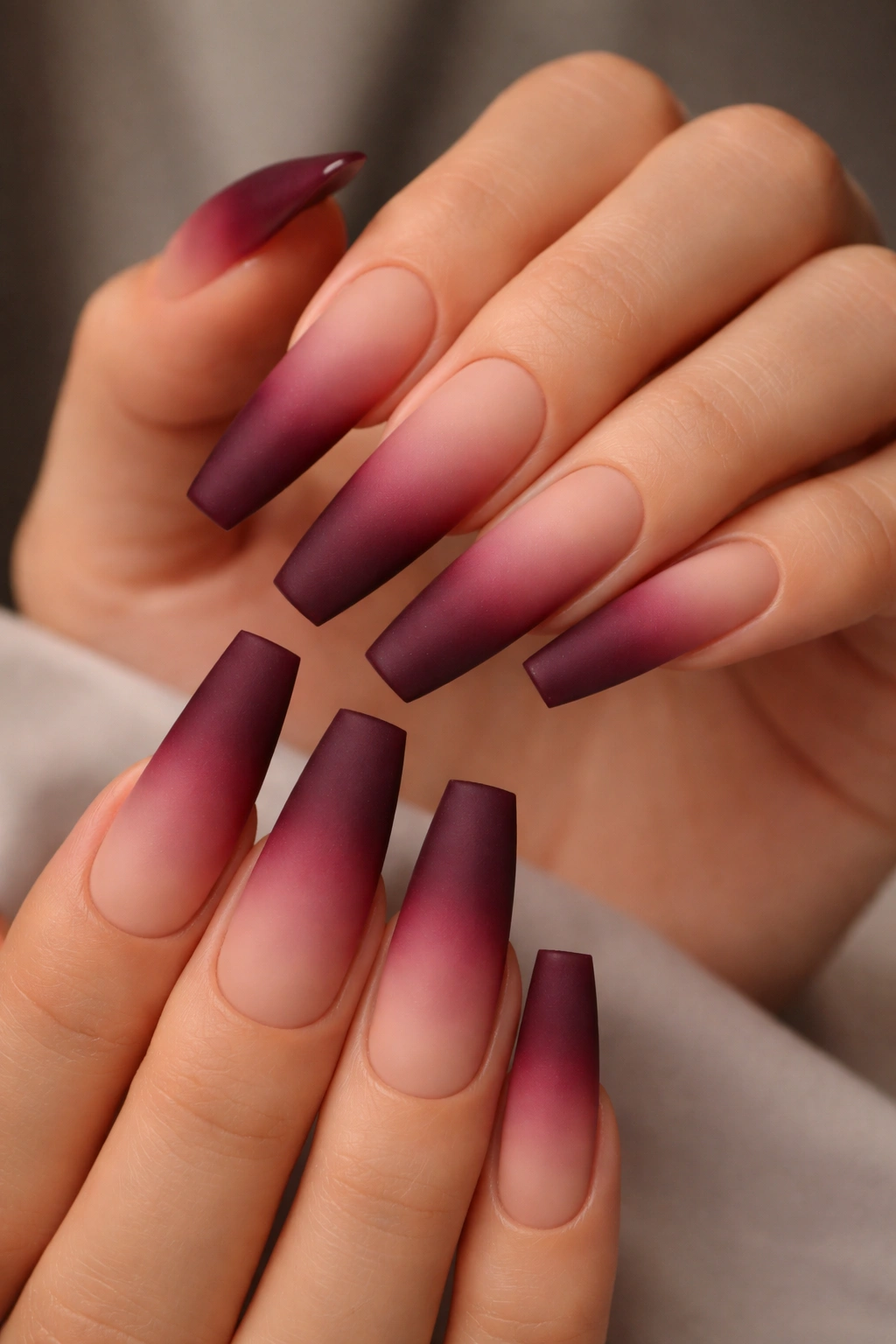 Close-up of coffin nails with nude-to-burgundy ombre and matte finish