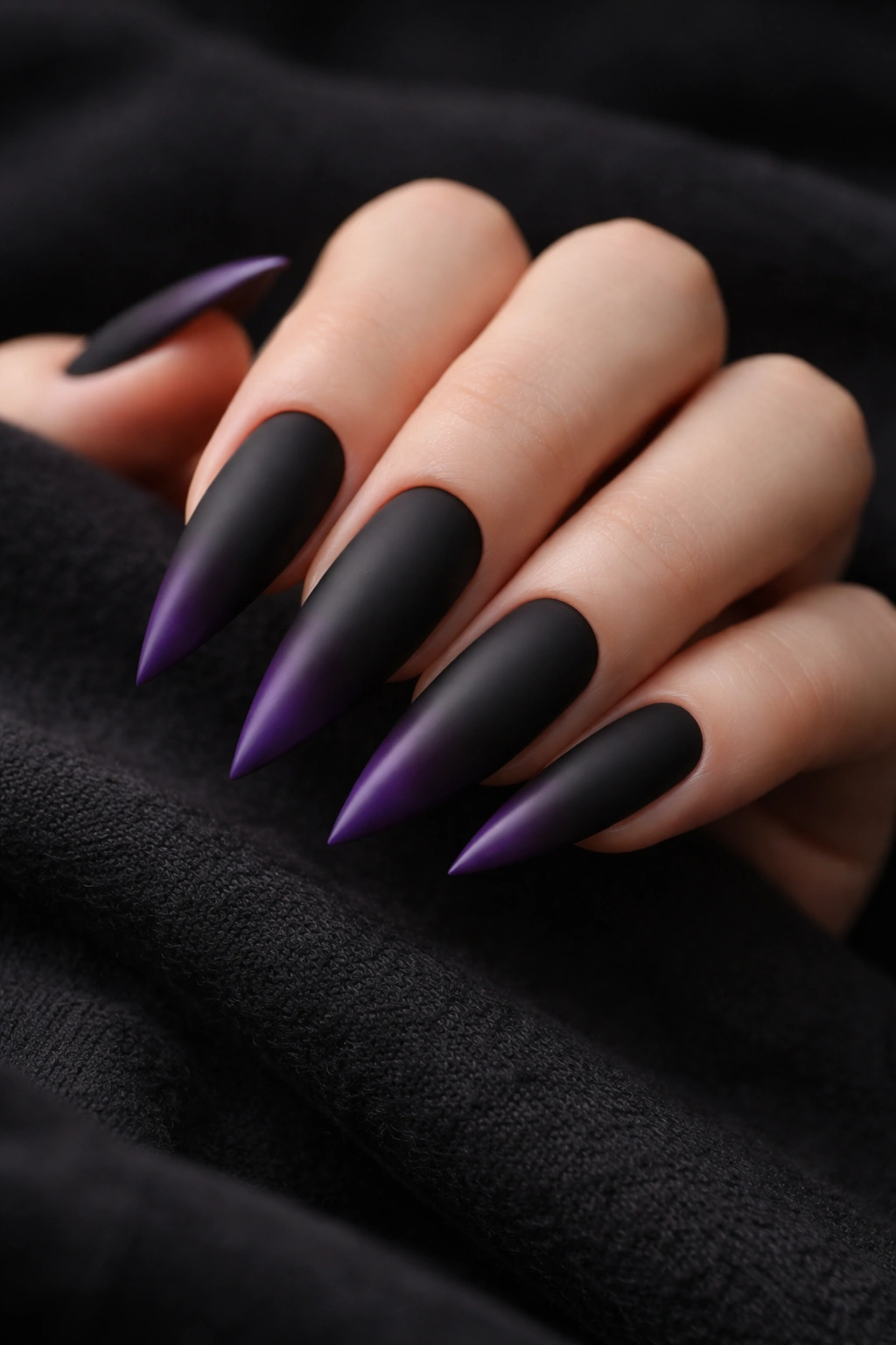Close-up of matte black to purple ombré stiletto nails