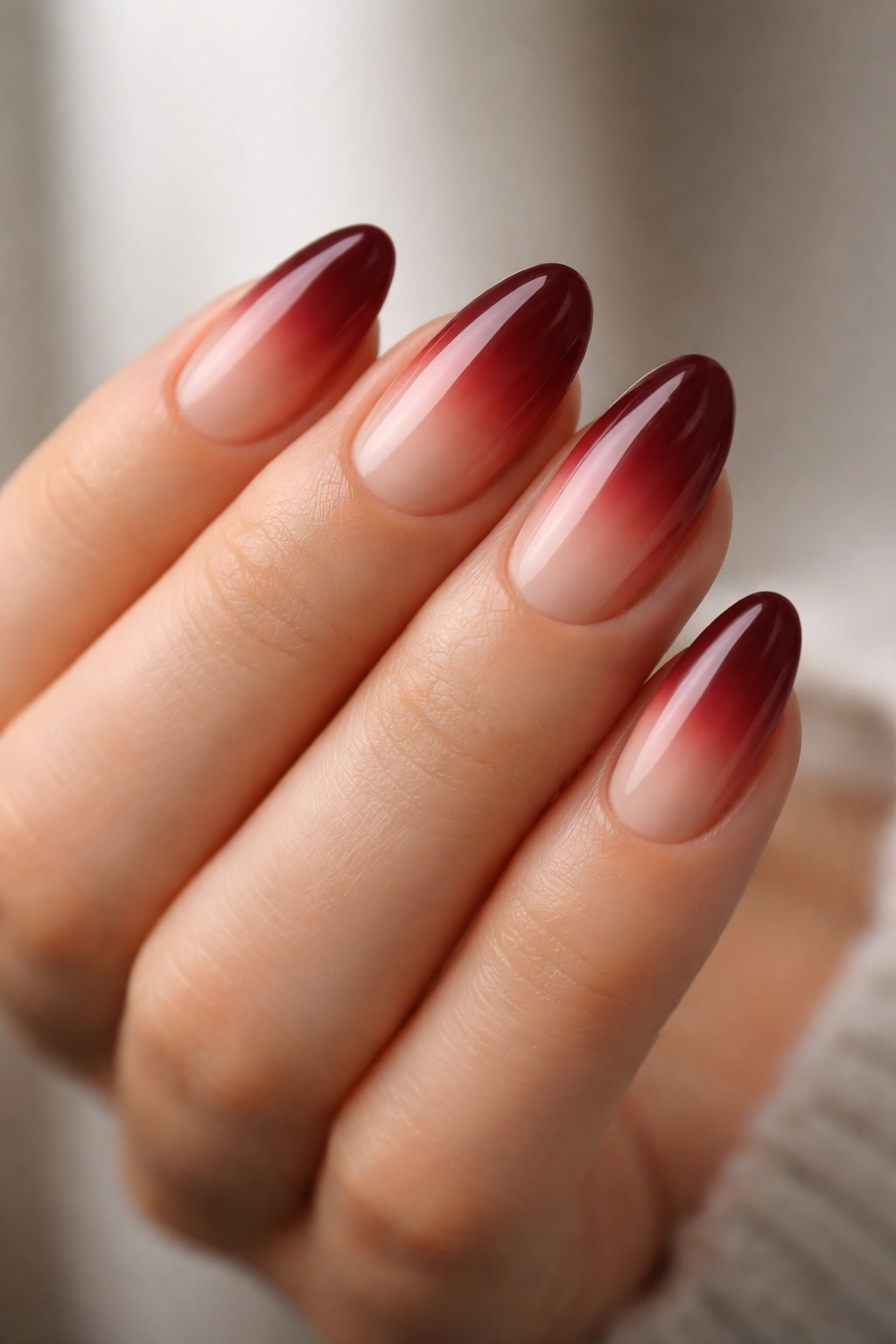 Close-up of short almond nails with nude-to-wine red ombre