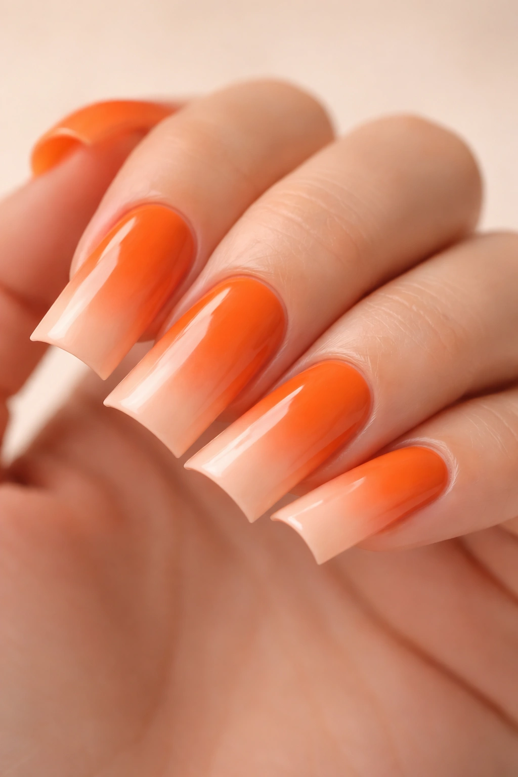 Close-up of duck nails with orange to peach ombré gradient