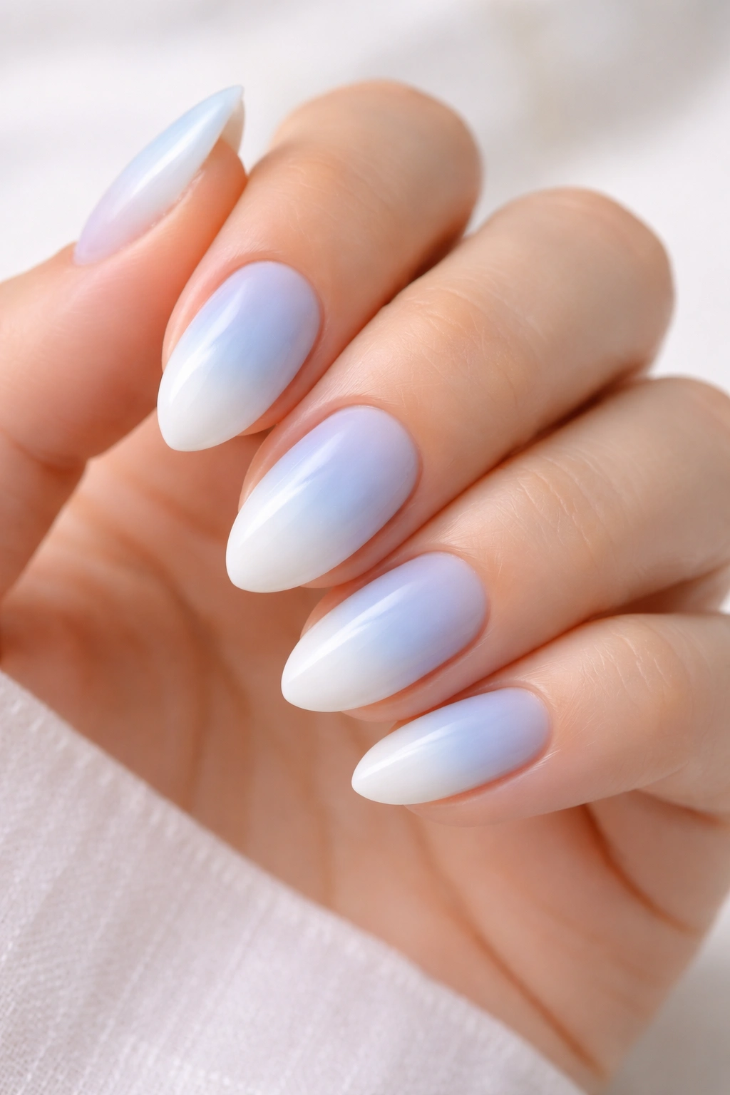 Short almond nails in powder blue to cloud white ombre on a neutral background