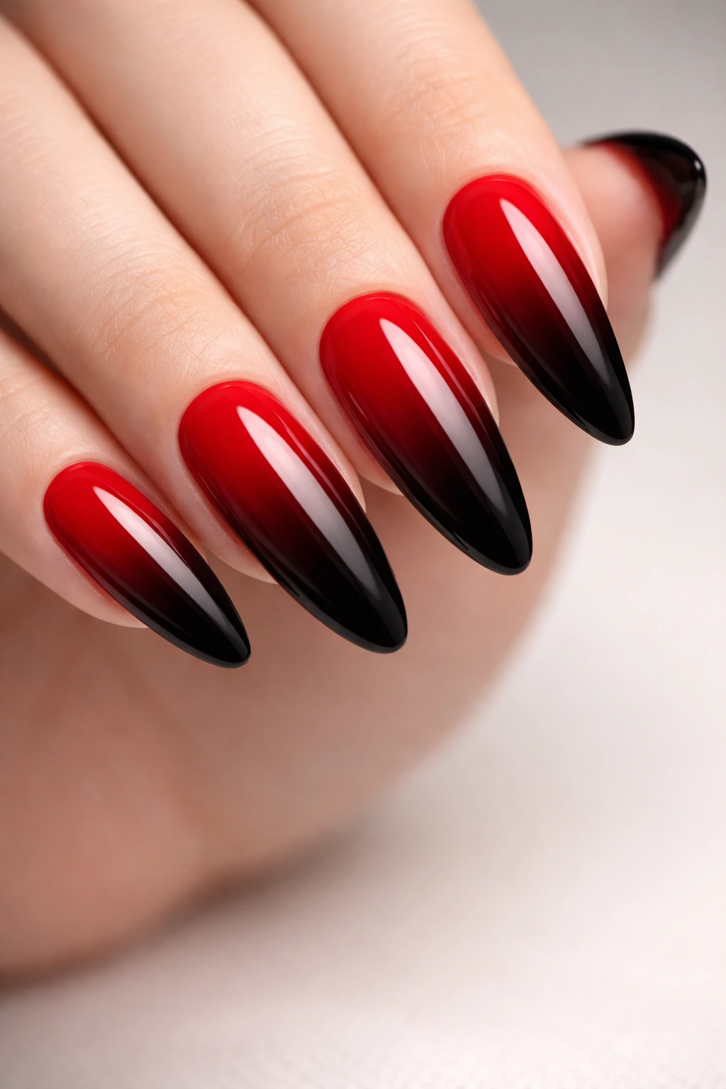 Close-up of nails with red-to-black ombre gradient and glossy finish