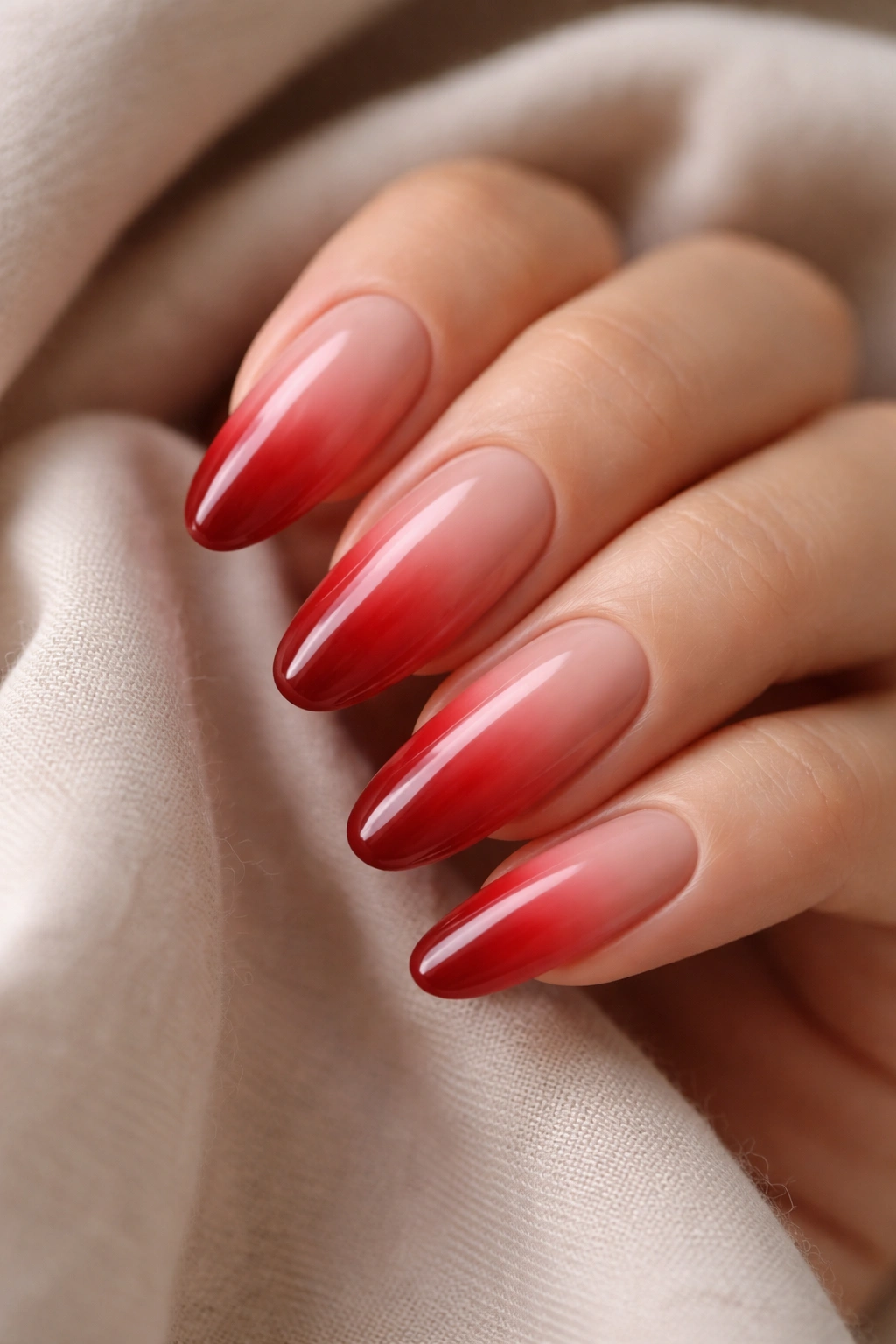 Close-up of long oval nails with red ombré gradient from nude to red.