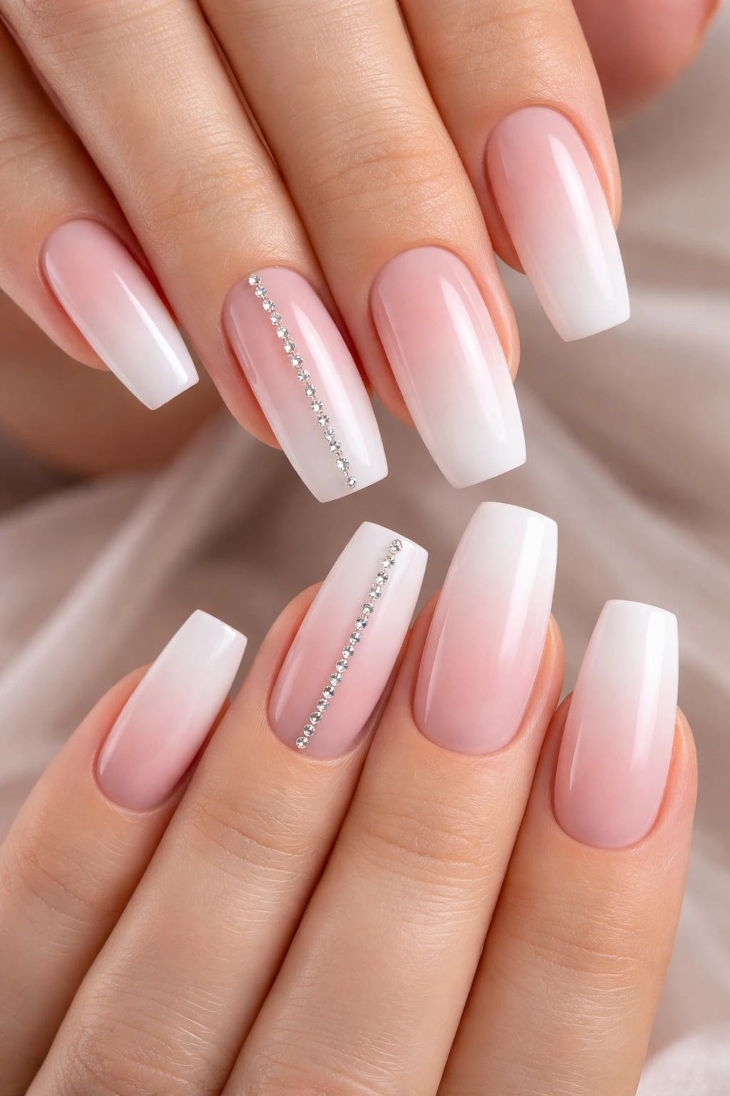 Soft pink to white ombre nails with a single rhinestone accent line