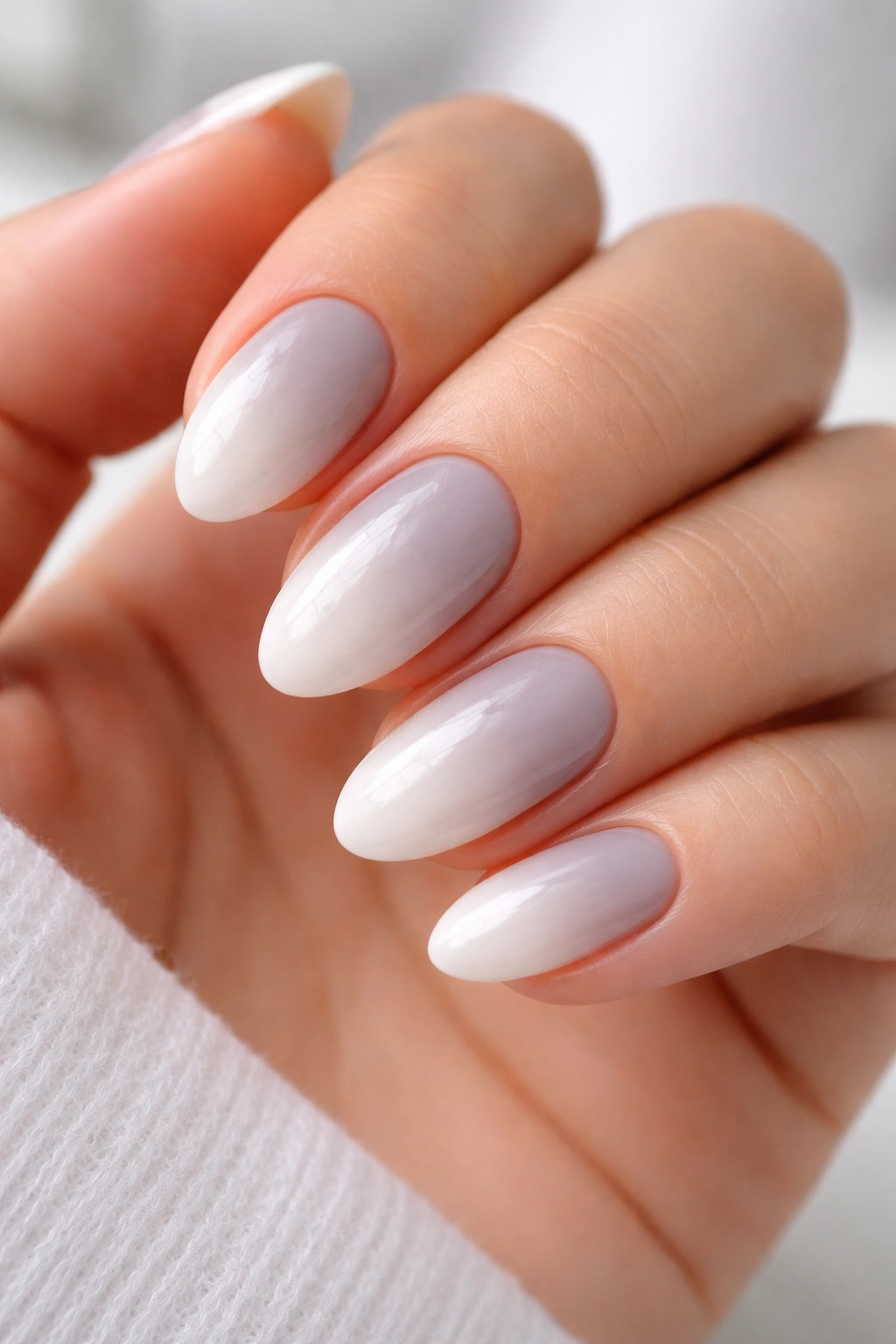 Short almond nails in soft gray to milky white ombre on a light background