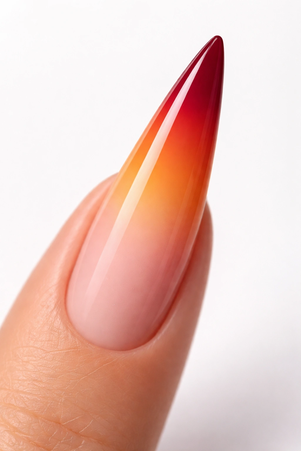 Close-up of a stiletto nail with an ombré sunset gradient from peach-pink to burgundy