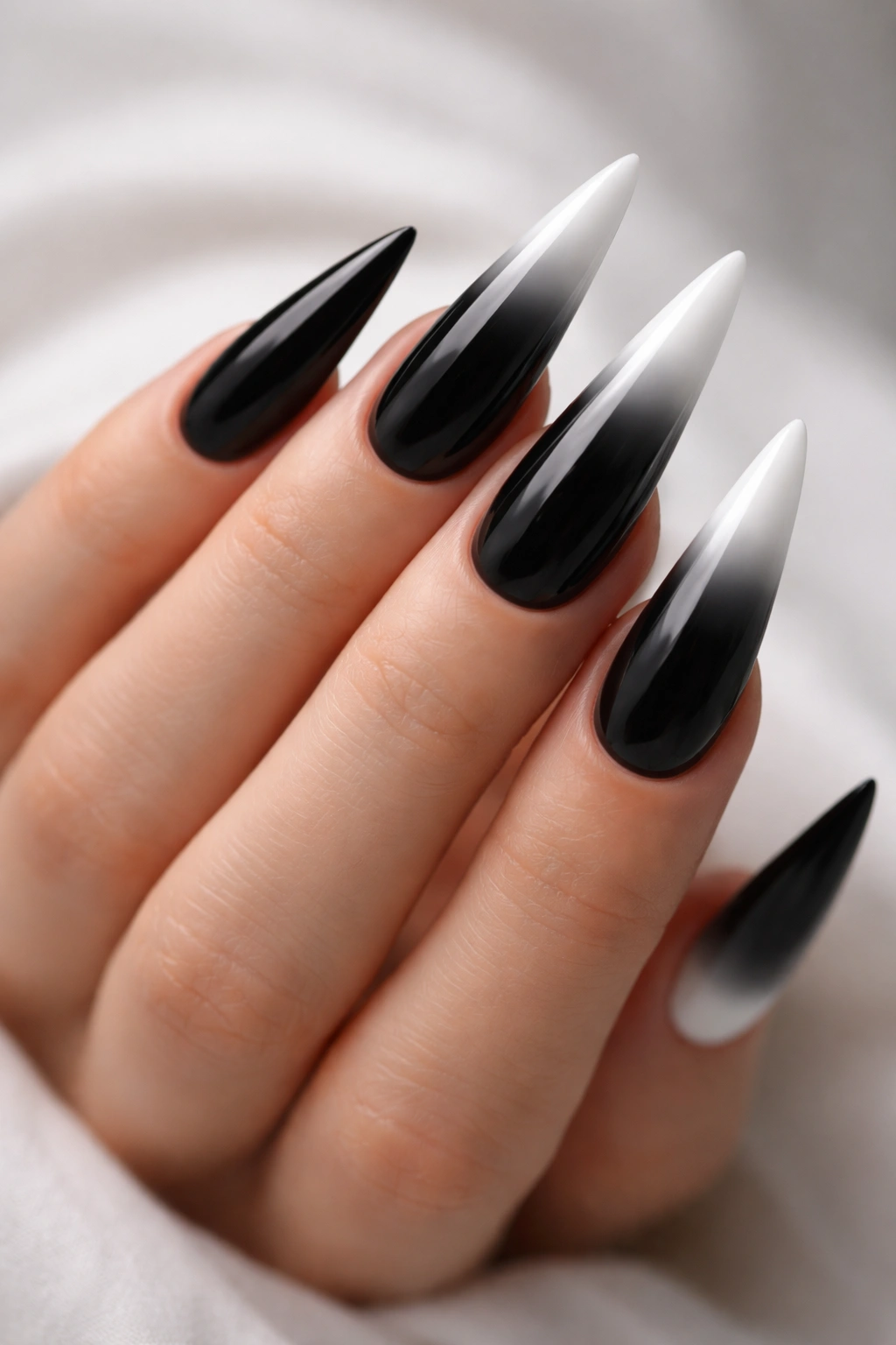 Close-up of long stiletto nails with black-to-white ombre gradient and glossy finish