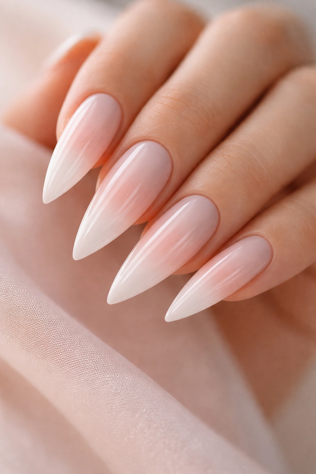 Close-up of white-to-peachy-pink ombre stiletto nails on a hand