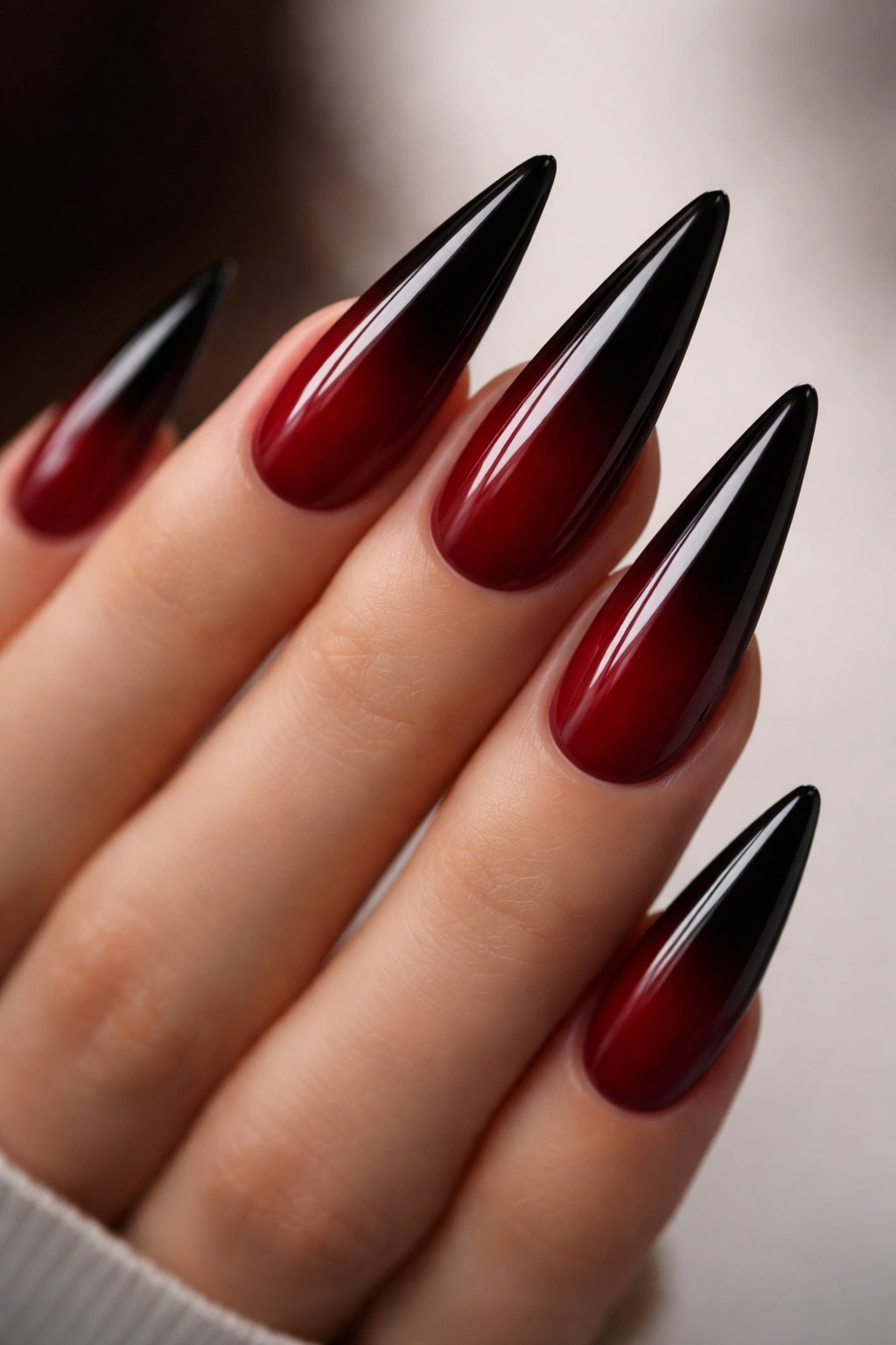 Close-up of deep red to black gradient on stiletto nails with glossy shine
