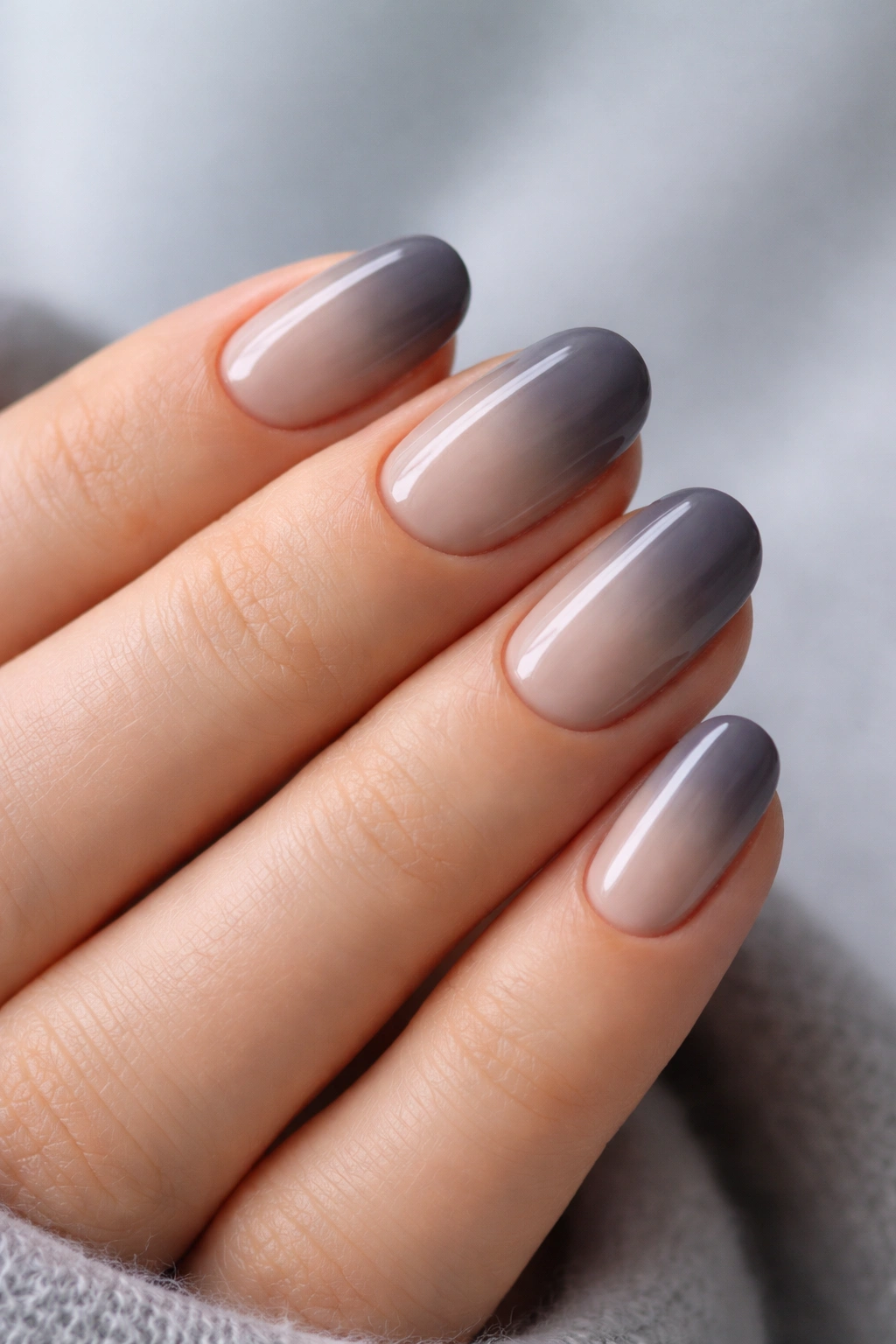 Close-up of short oval nails in taupe to smoke gray ombre