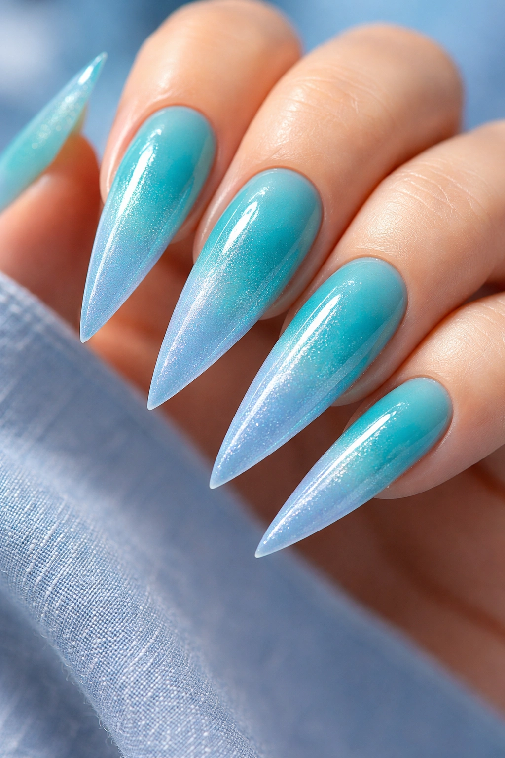 Close-up of teal to blue ombre stiletto nails with smooth gradient