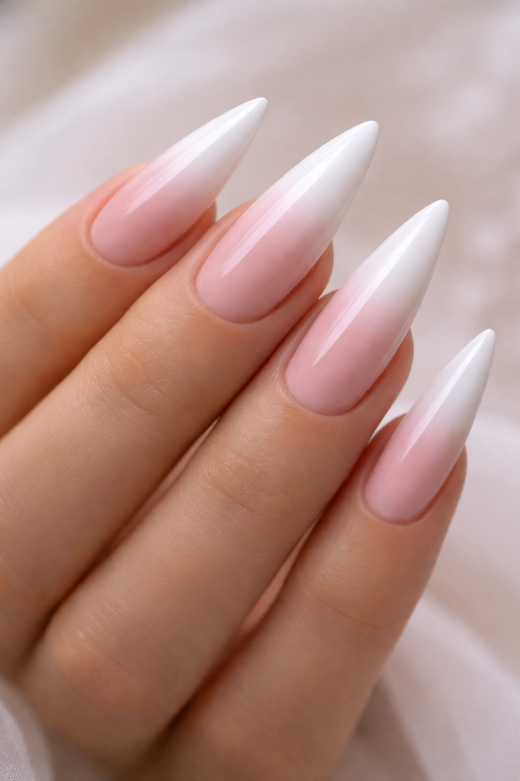 Close-up of ombre nails transitioning from white to blush pink
