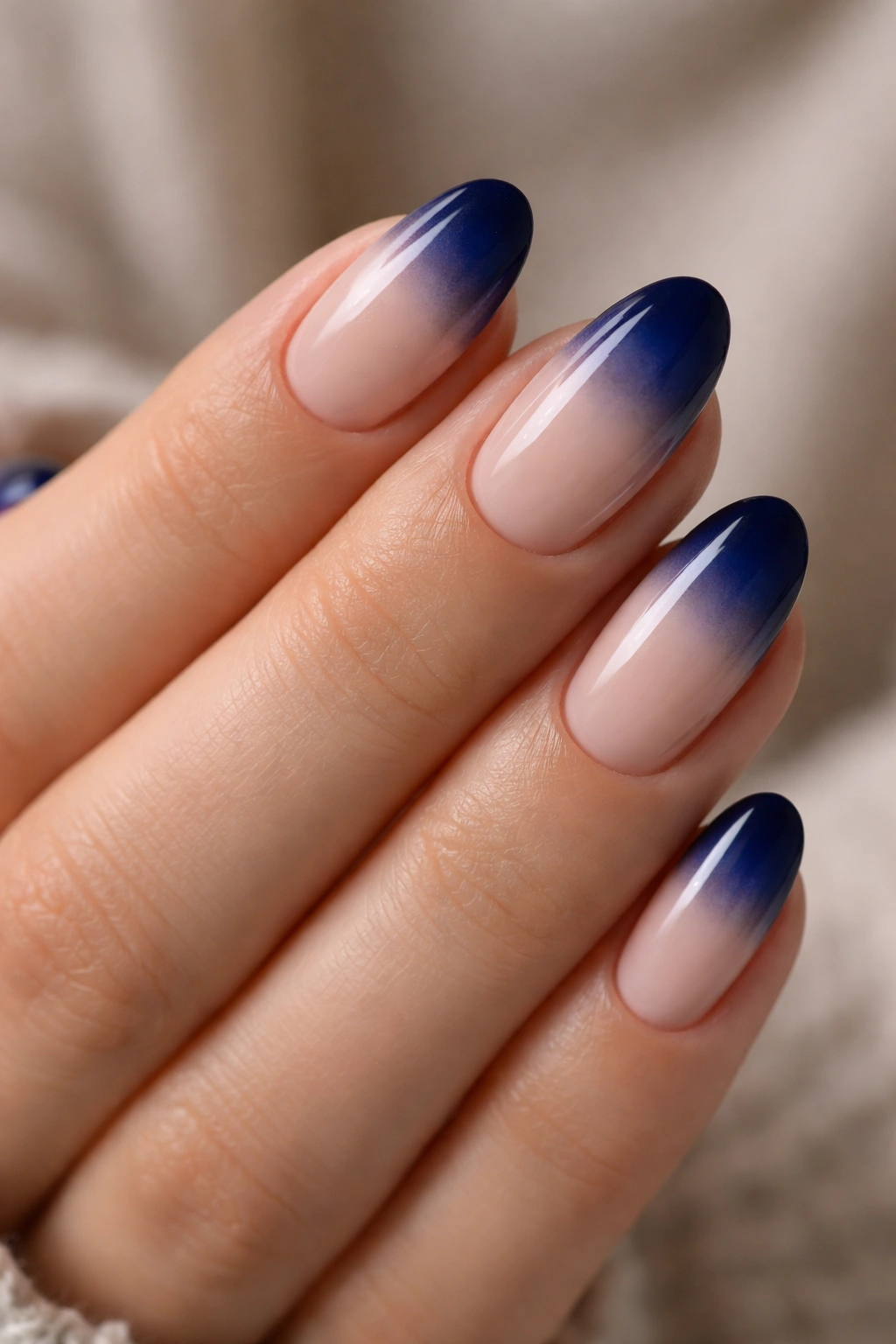 Close-up of short almond nails with navy to nude ombre gradient