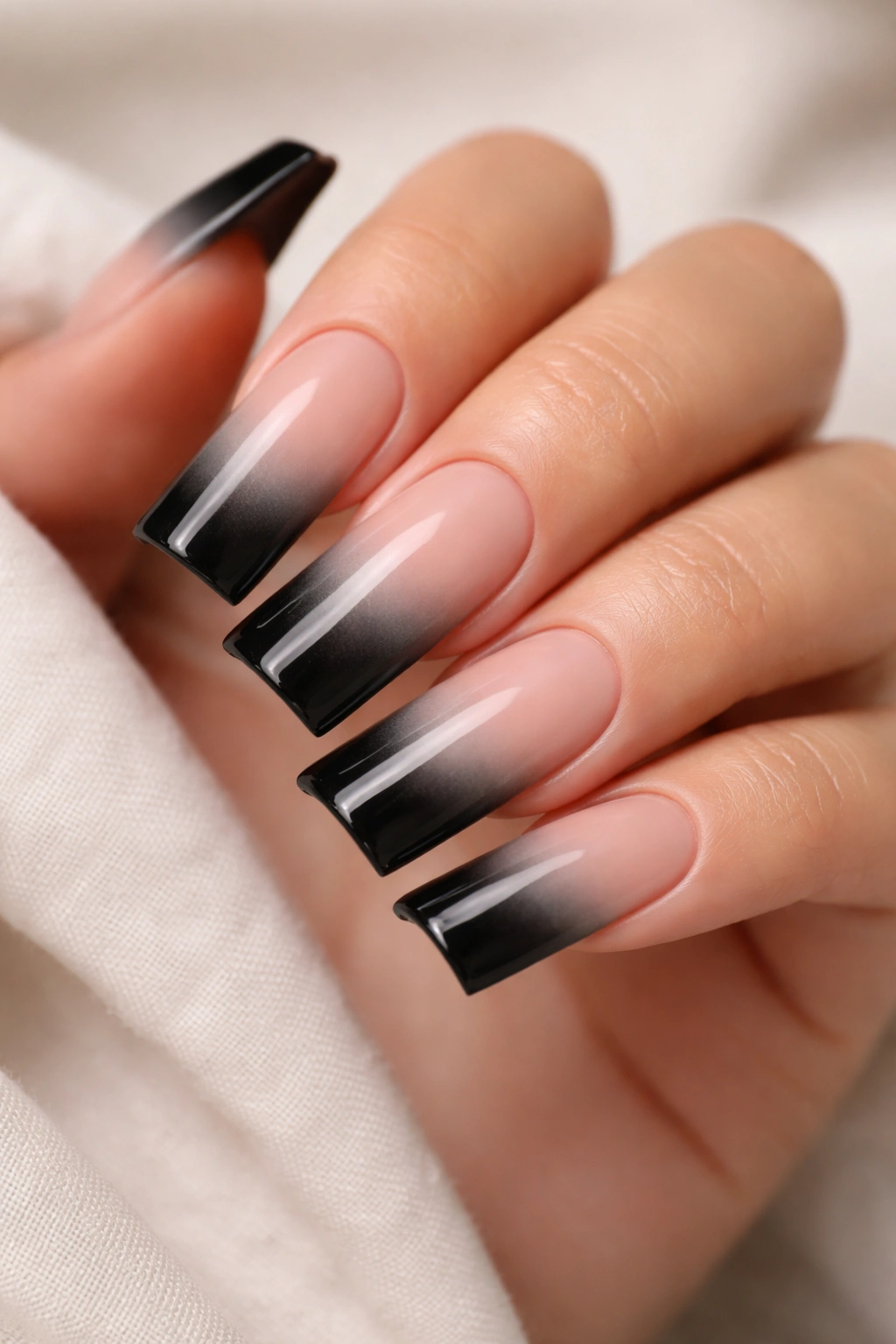 Close-up of duck-shaped nails with nude-to-black ombré fade