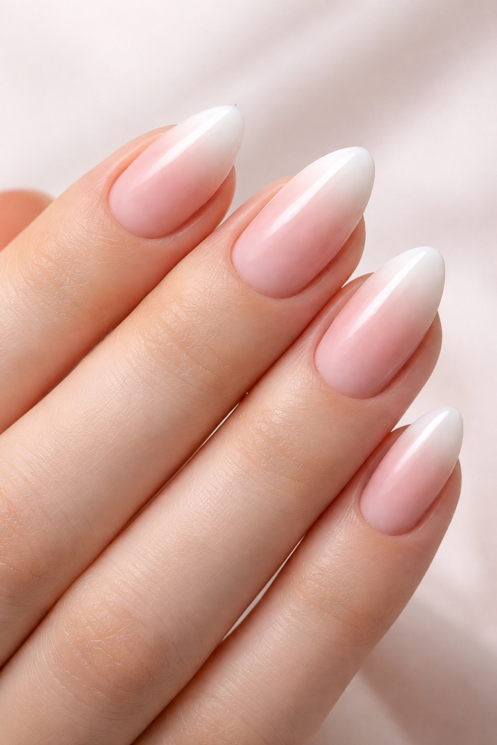 Close-up of ombré pink to white almond gradient nails