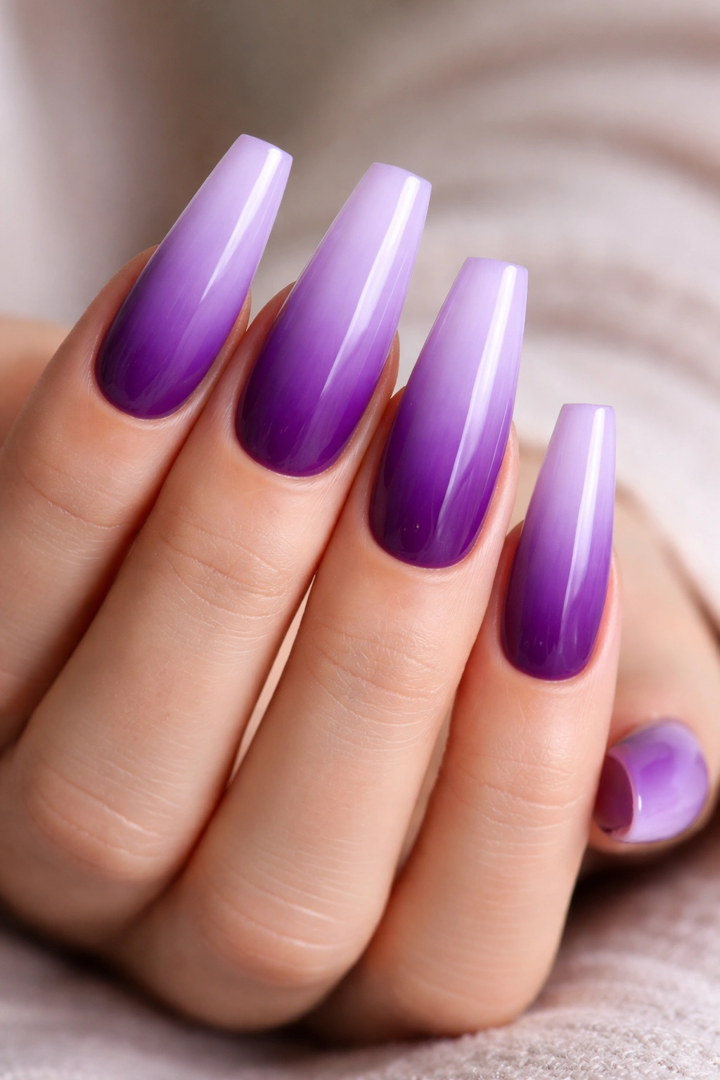Close-up of coffin nails with an ombre purple gradient from pale lavender to deep purple