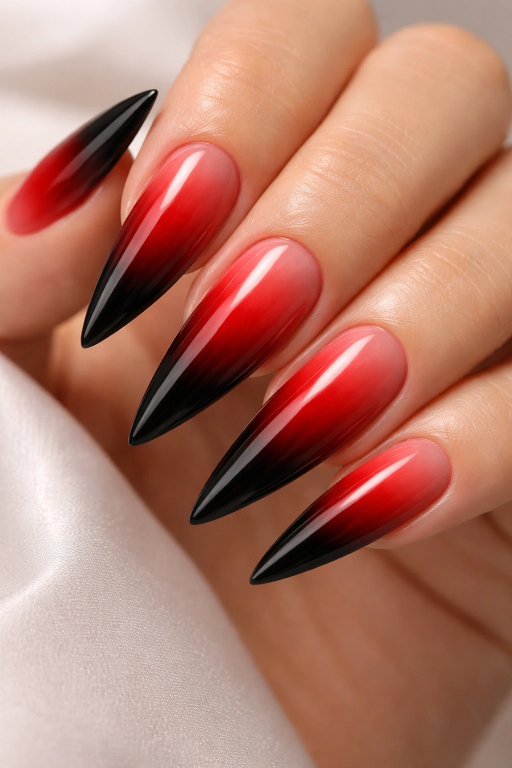 Close-up of ombré stiletto nails transitioning from red to black