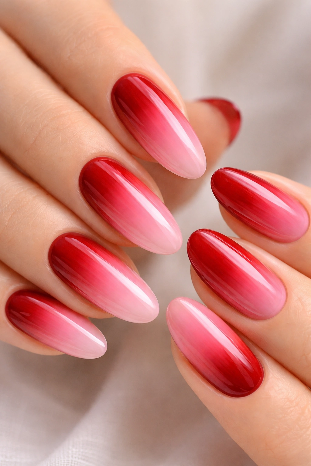 Close-up of ombré red to pink gradient on a long oval nail
