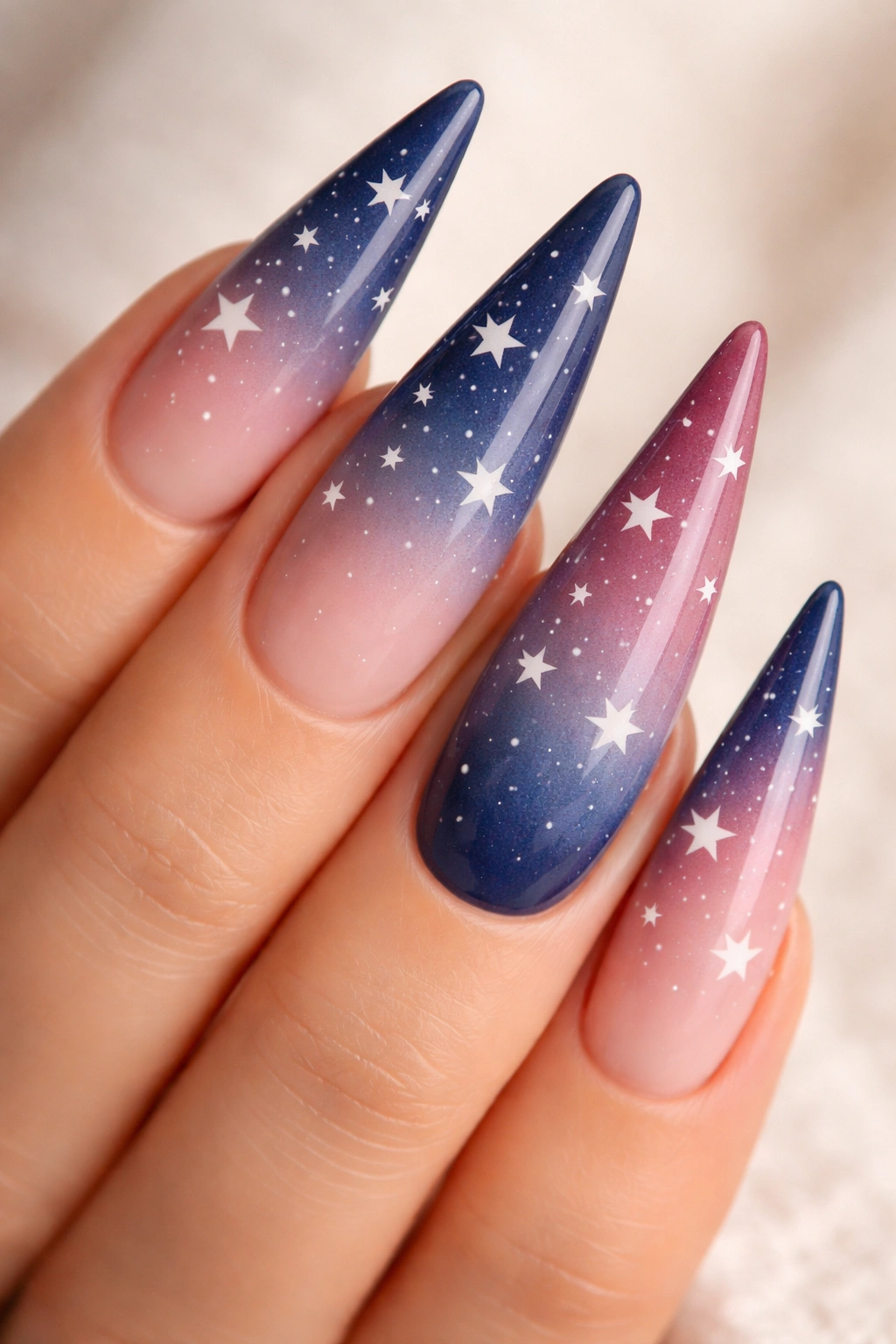 Close-up of ombré stiletto nails with gradient colors and star accents on a neutral background