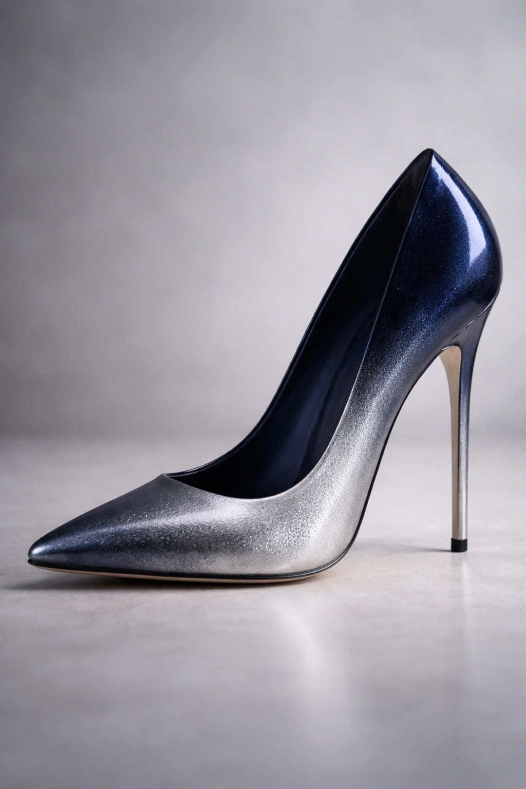 Navy-to-silver ombre stiletto on a gray studio background with reflective shine