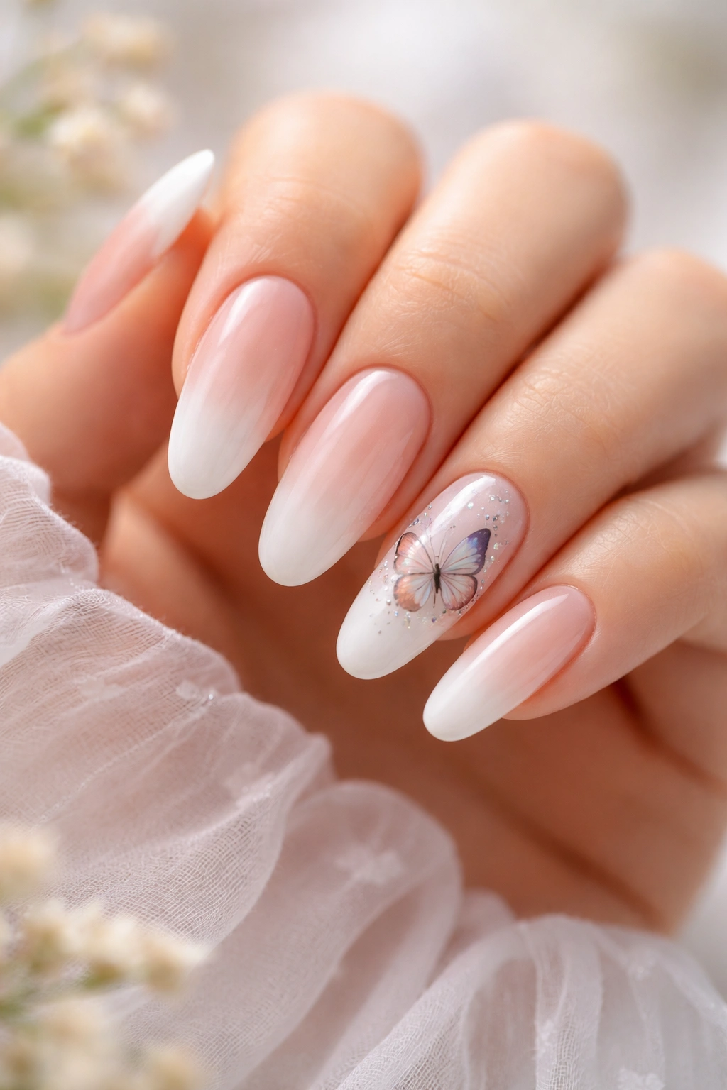 Long oval nails with nude-to-white ombre and hand-painted butterflies