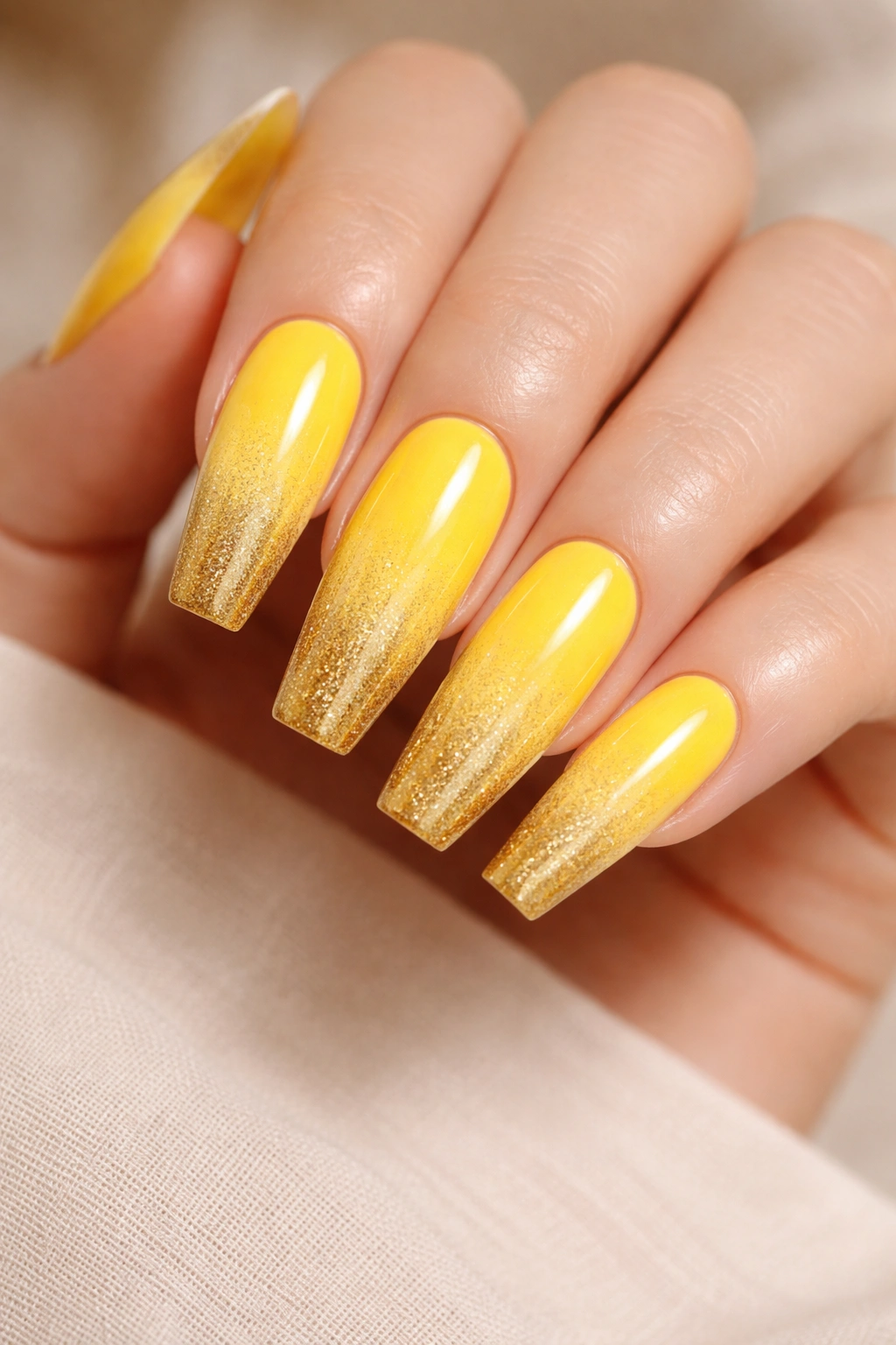 Close-up of coffin nails with yellow to gold ombre gradient.