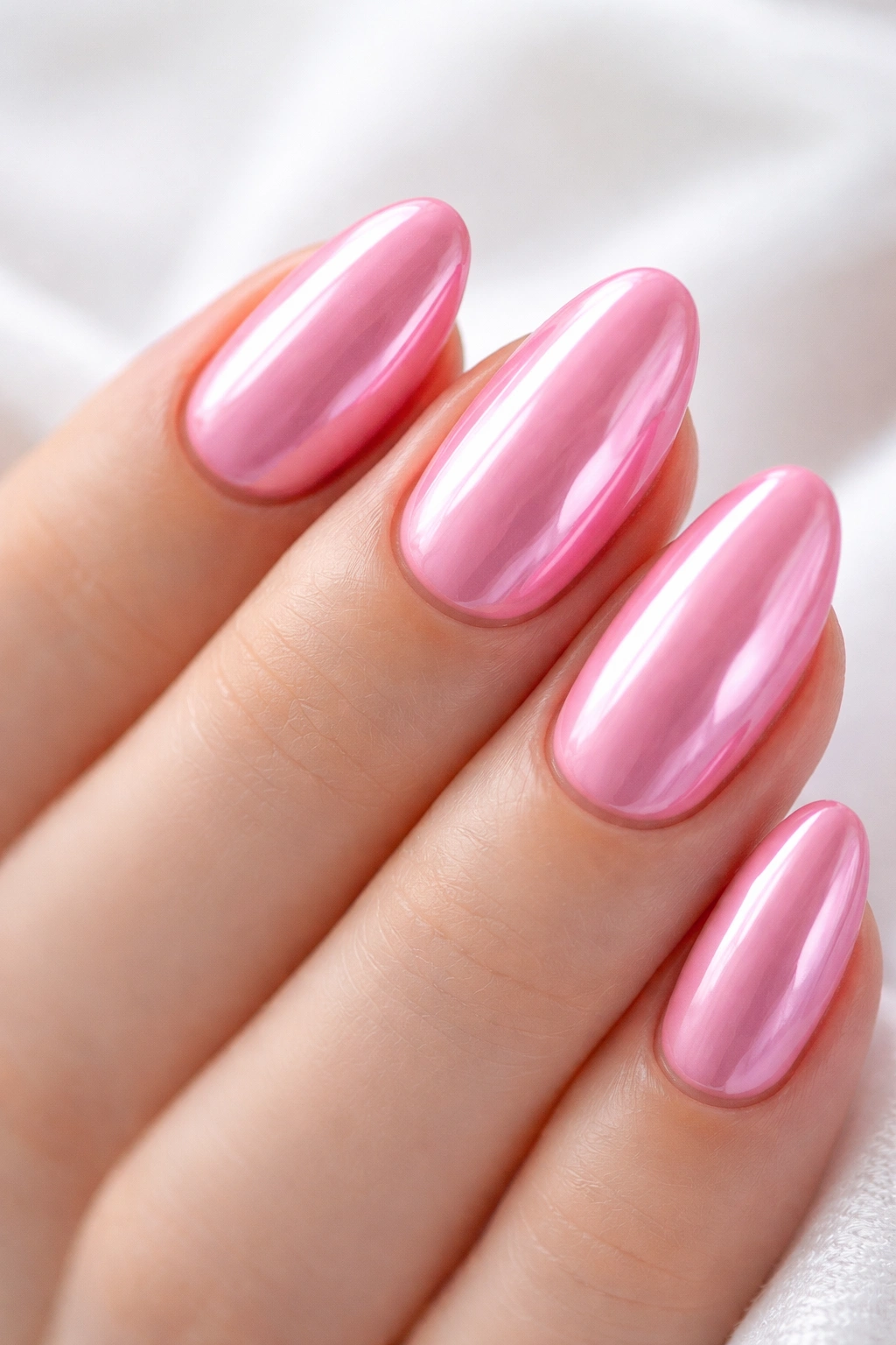 Close-up of a short almond nail in saturated pink with chrome overlay