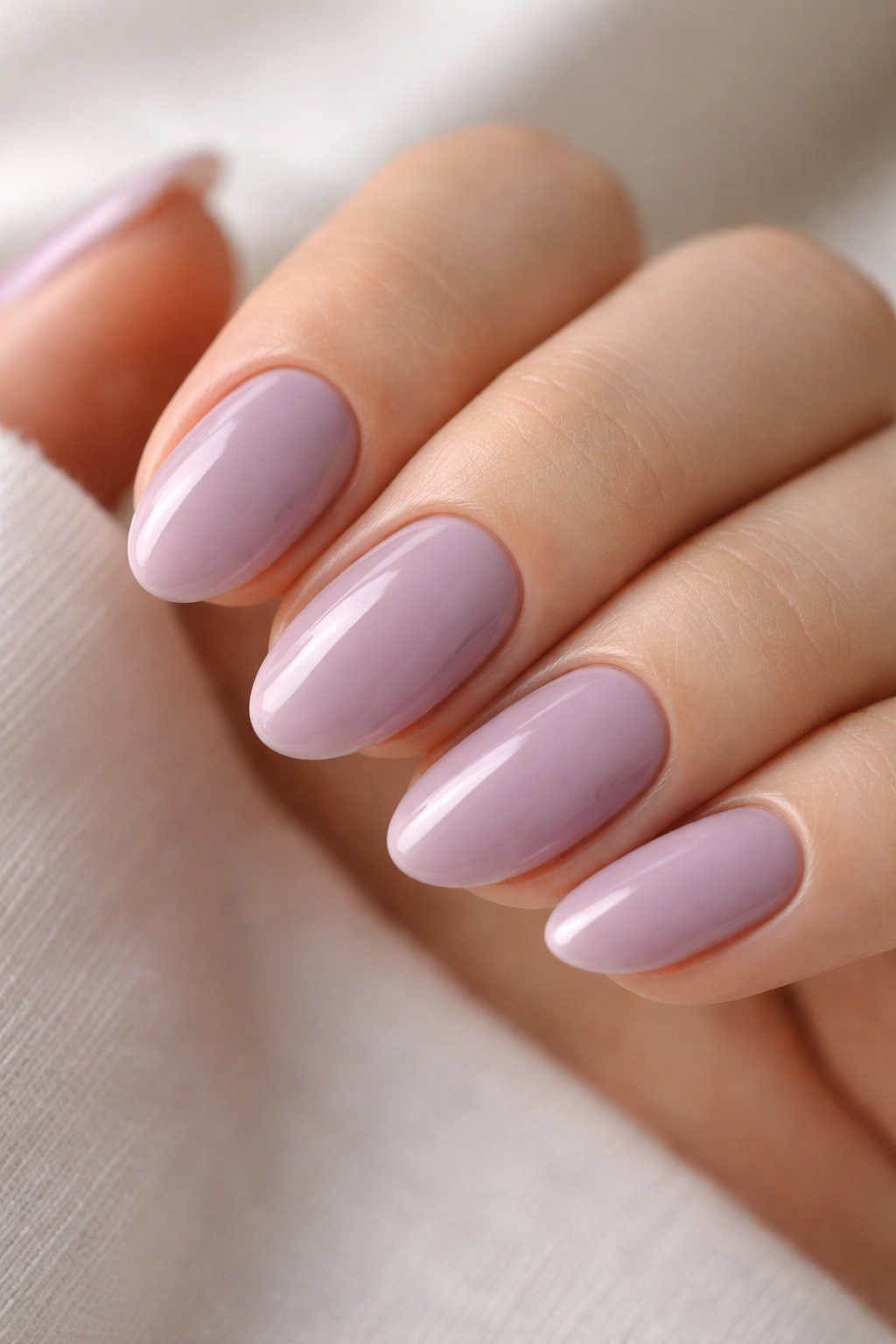Close-up of short almond nails in opaque lilac-mauve with glossy finish
