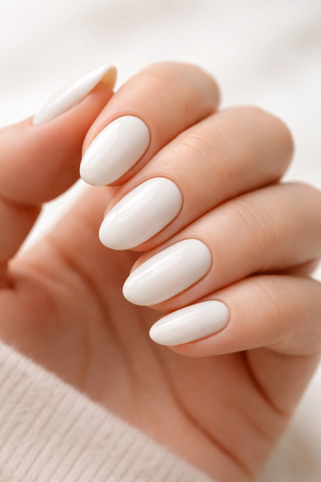 Close-up of opaque white short almond nails with ivory tint