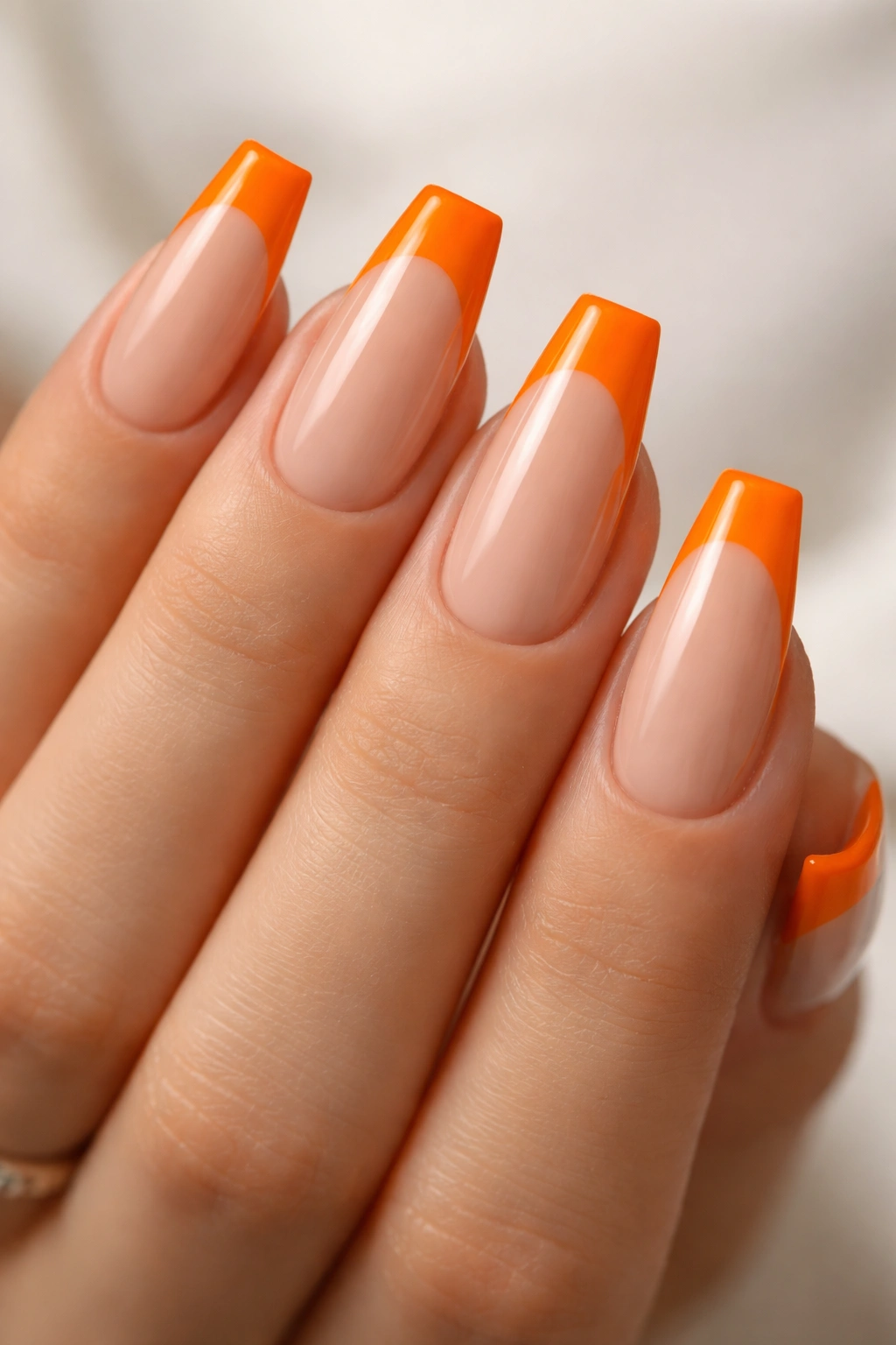 Nude base nails with chunky orange tips on ballerina nails