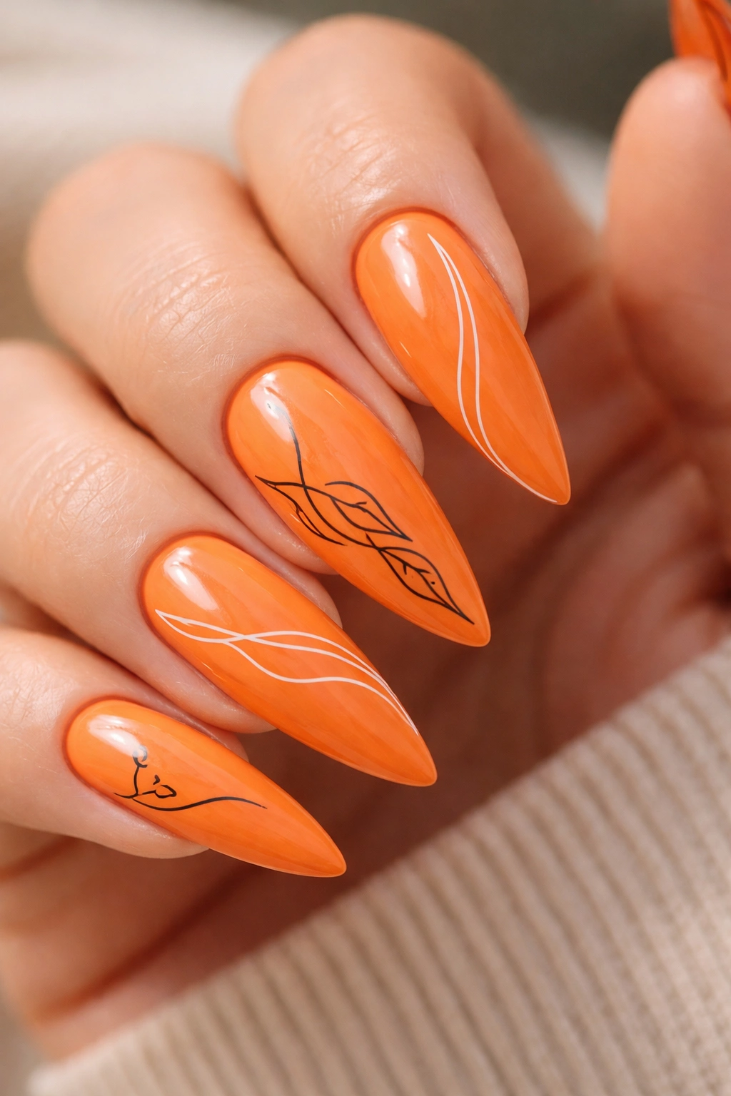 Close-up of orange stiletto nails with minimalist line art