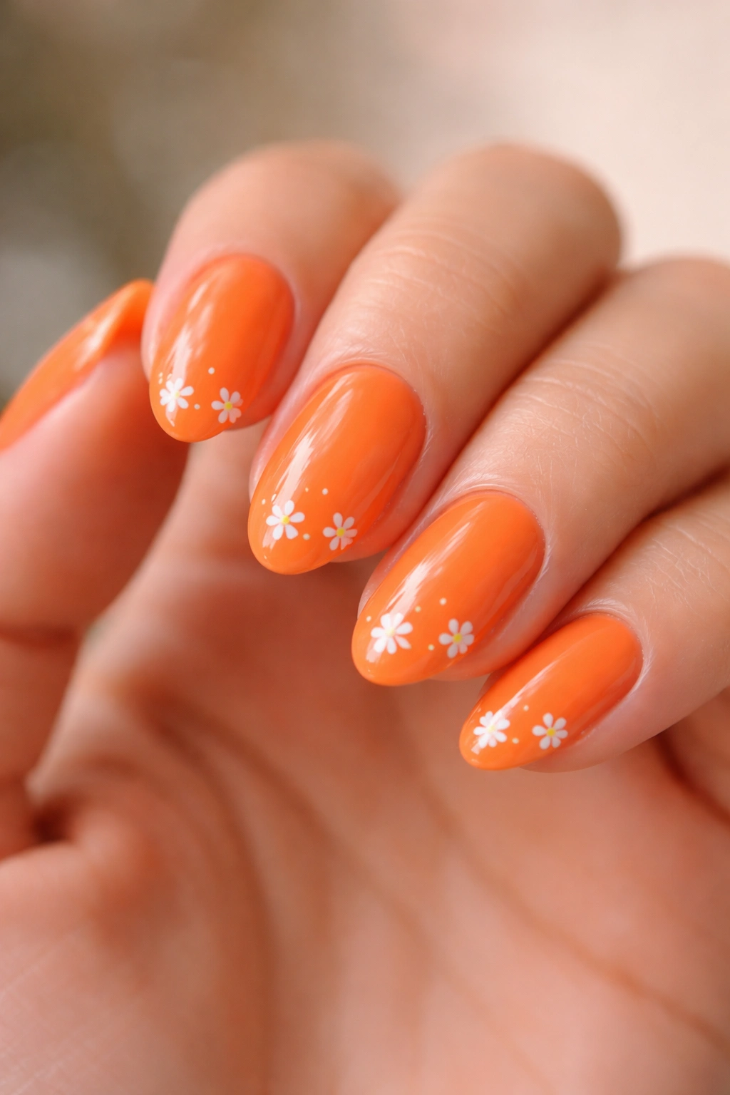 Close-up of orange nails with tiny white flowers on short almond nails
