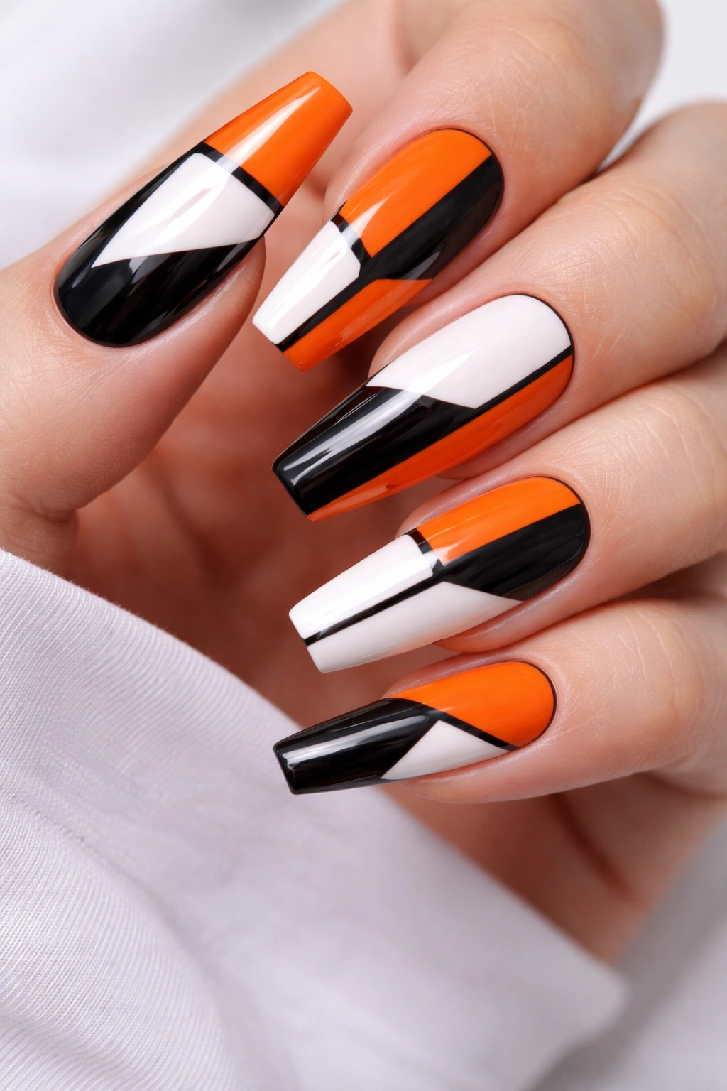 Close-up of hot orange coffin nails with black and white geometric color blocks