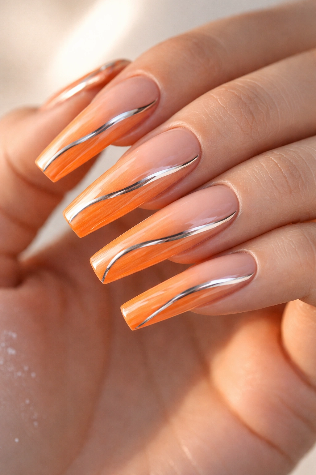 Long coffin nails with tangerine ombre and chrome accents.