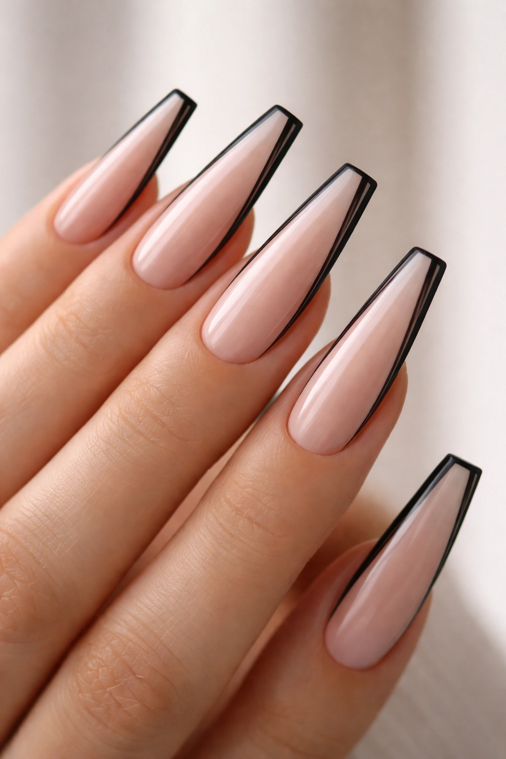 Close-up of long nails with black outline French tips on nude base