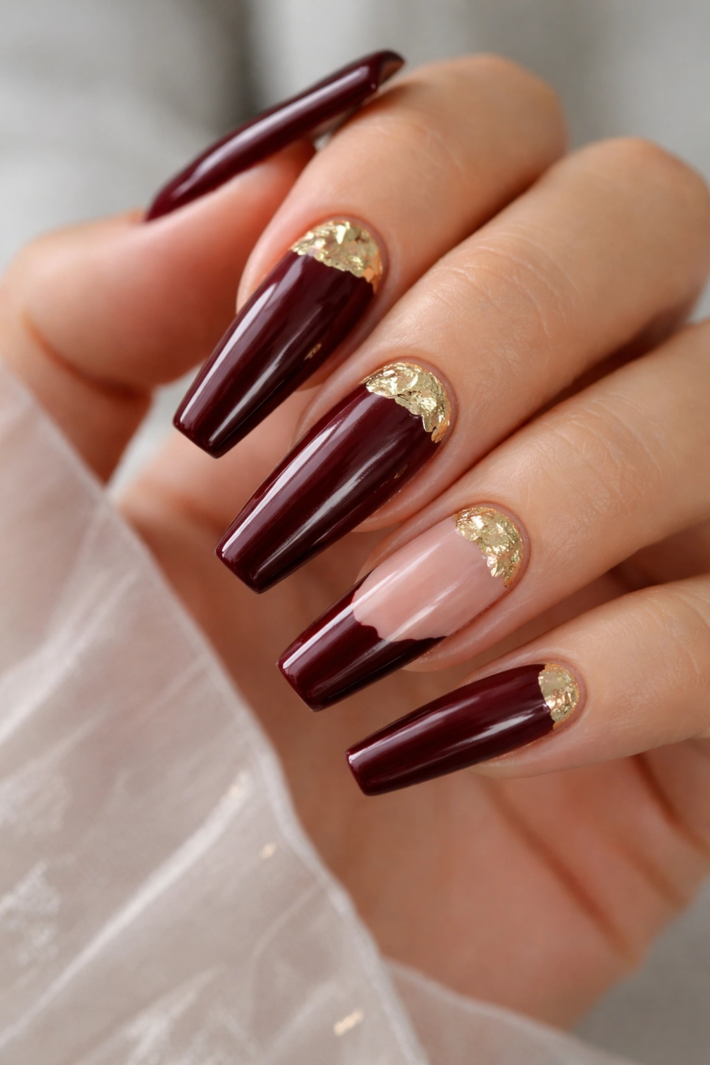 Oxblood French tips with small broken gold foil half-moon accents