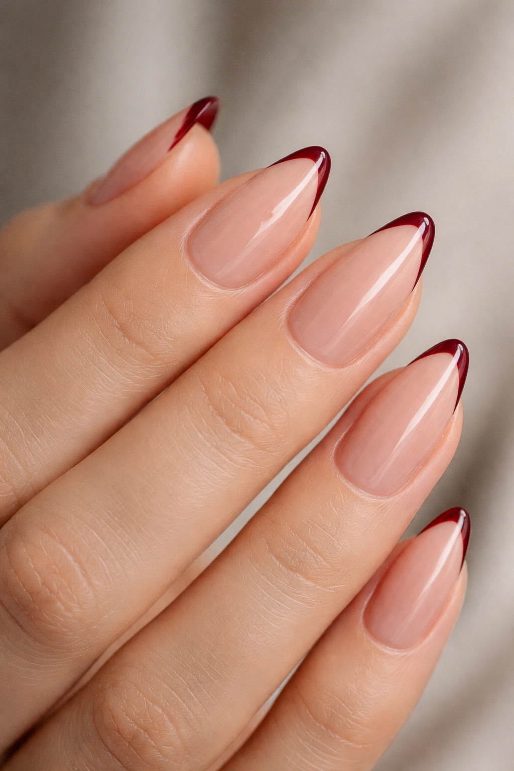 Close-up of almond nails with a slim oxblood micro French tip