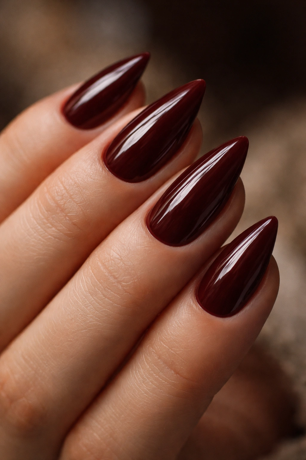 Close-up of short almond nails in oxblood with a sharp almond tip